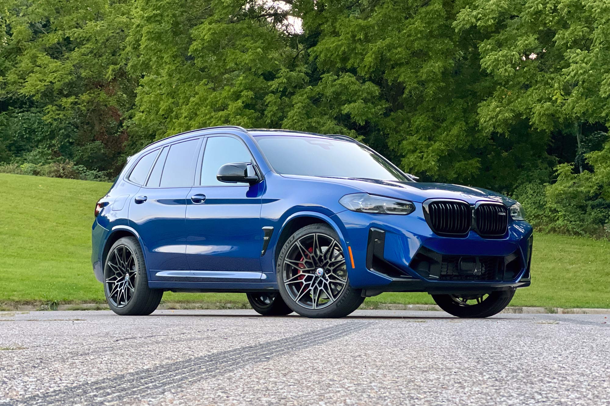 2023 BMW X3 M in Le Mans Blue front quarter parked in front of grass