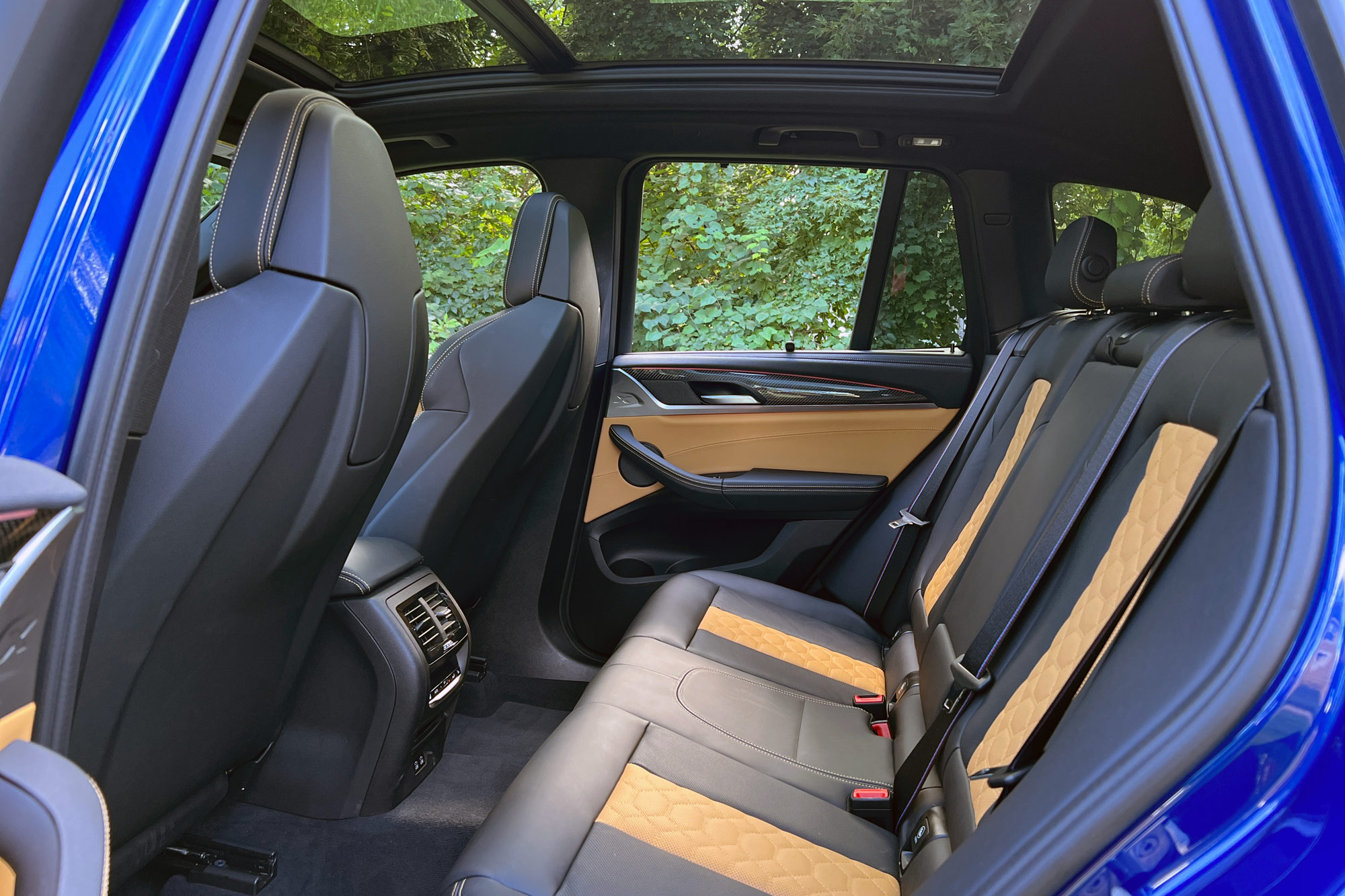 2023 BMW X3 M in Le Mans Blue backseats in brown and black with view of forest