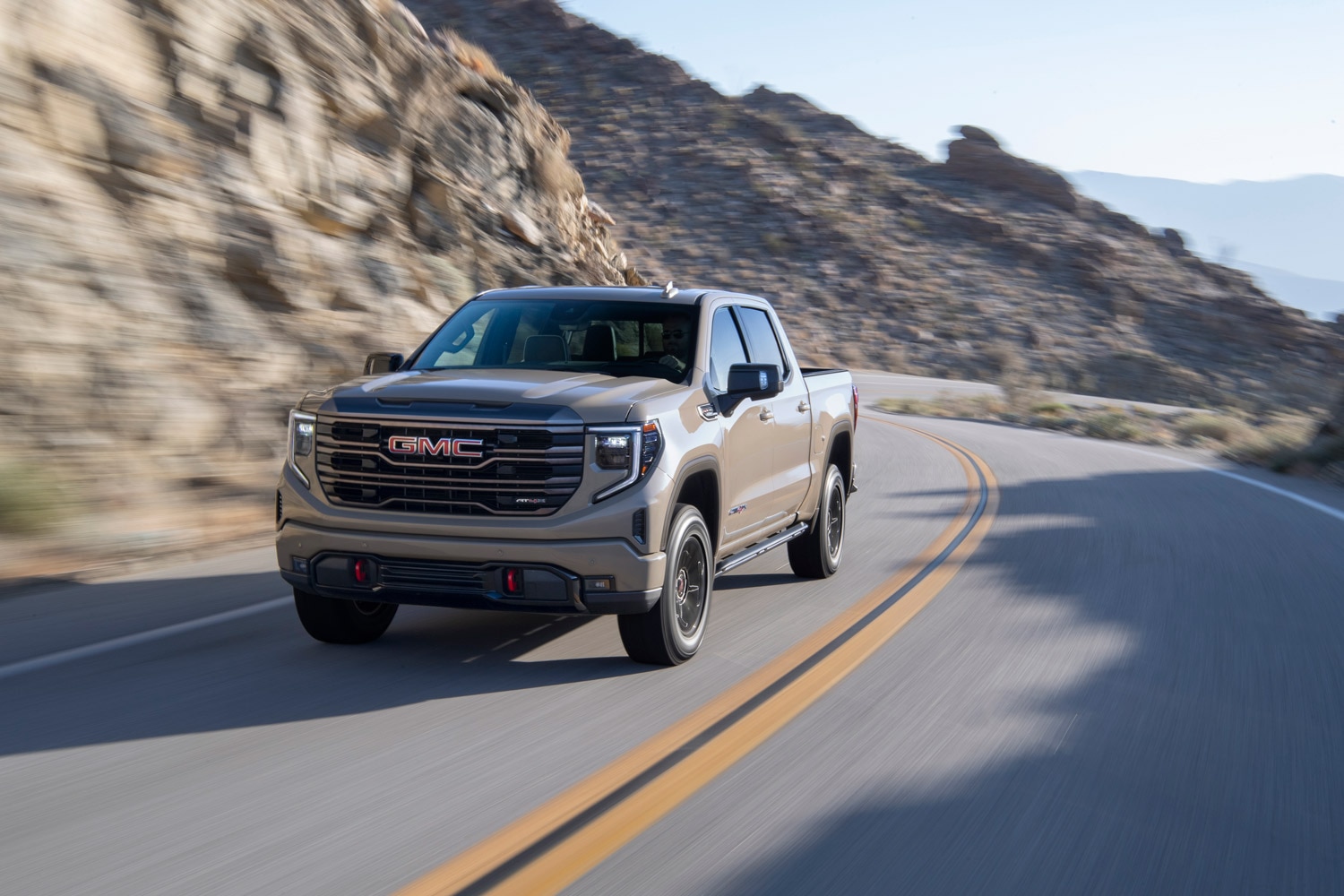 2023 GMC Sierra 1500 driving along a winding road in the mountains.