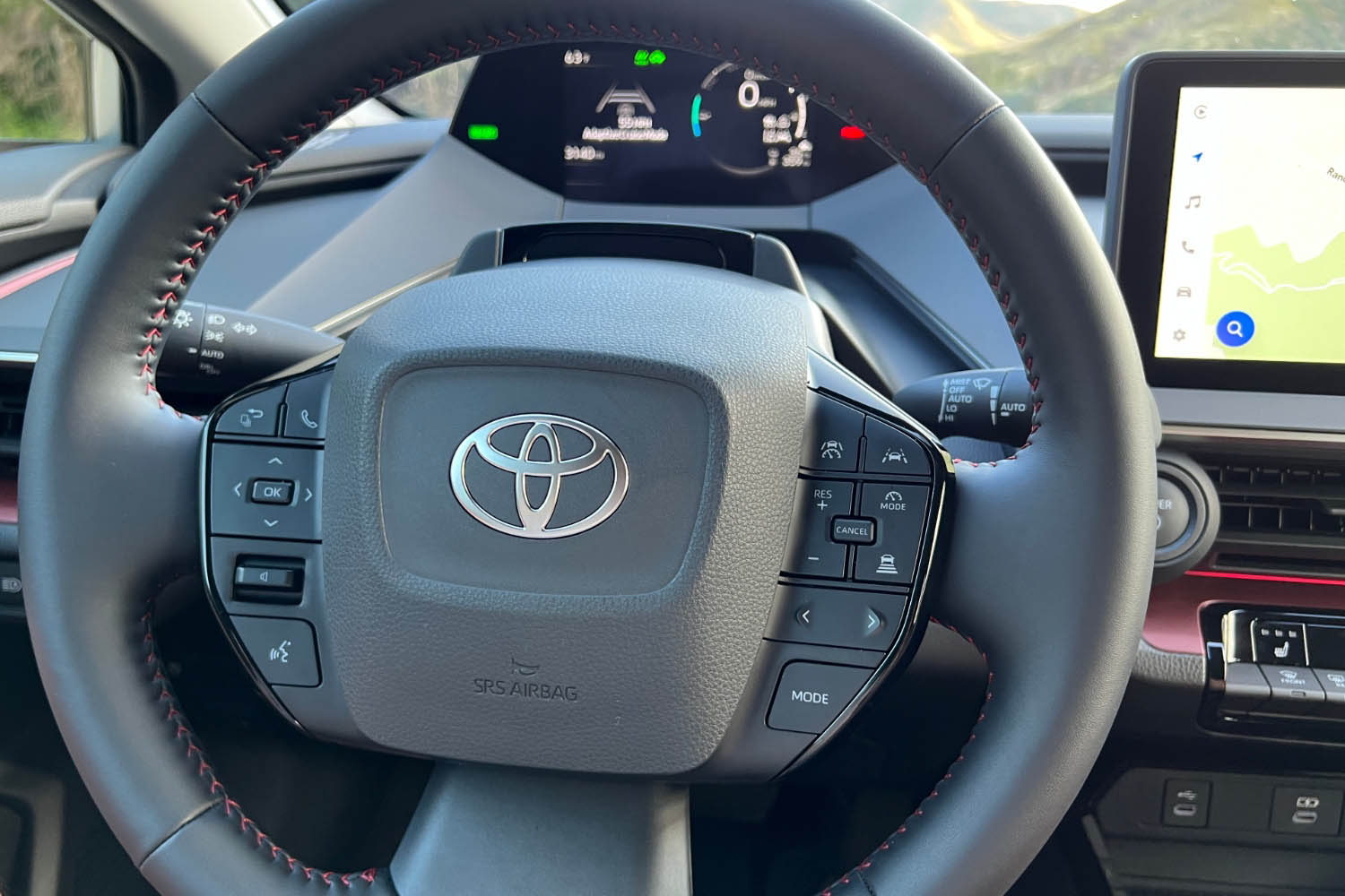 Steering wheel of the 2023 Toyota Prius Prime with gauge cluster and infotainment screen in background