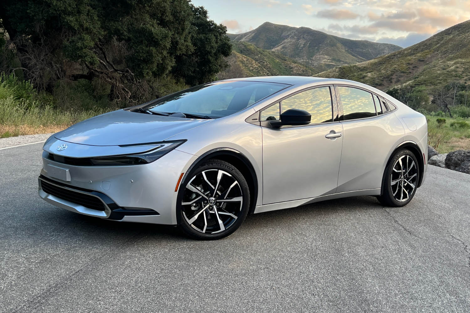 Front left quarter shot of silver 2023 Toyota Prius Prime parked on road in front of mountains