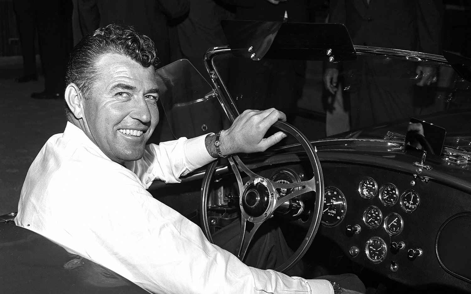 Carroll Shelby seated in the driver's seat of a roadster