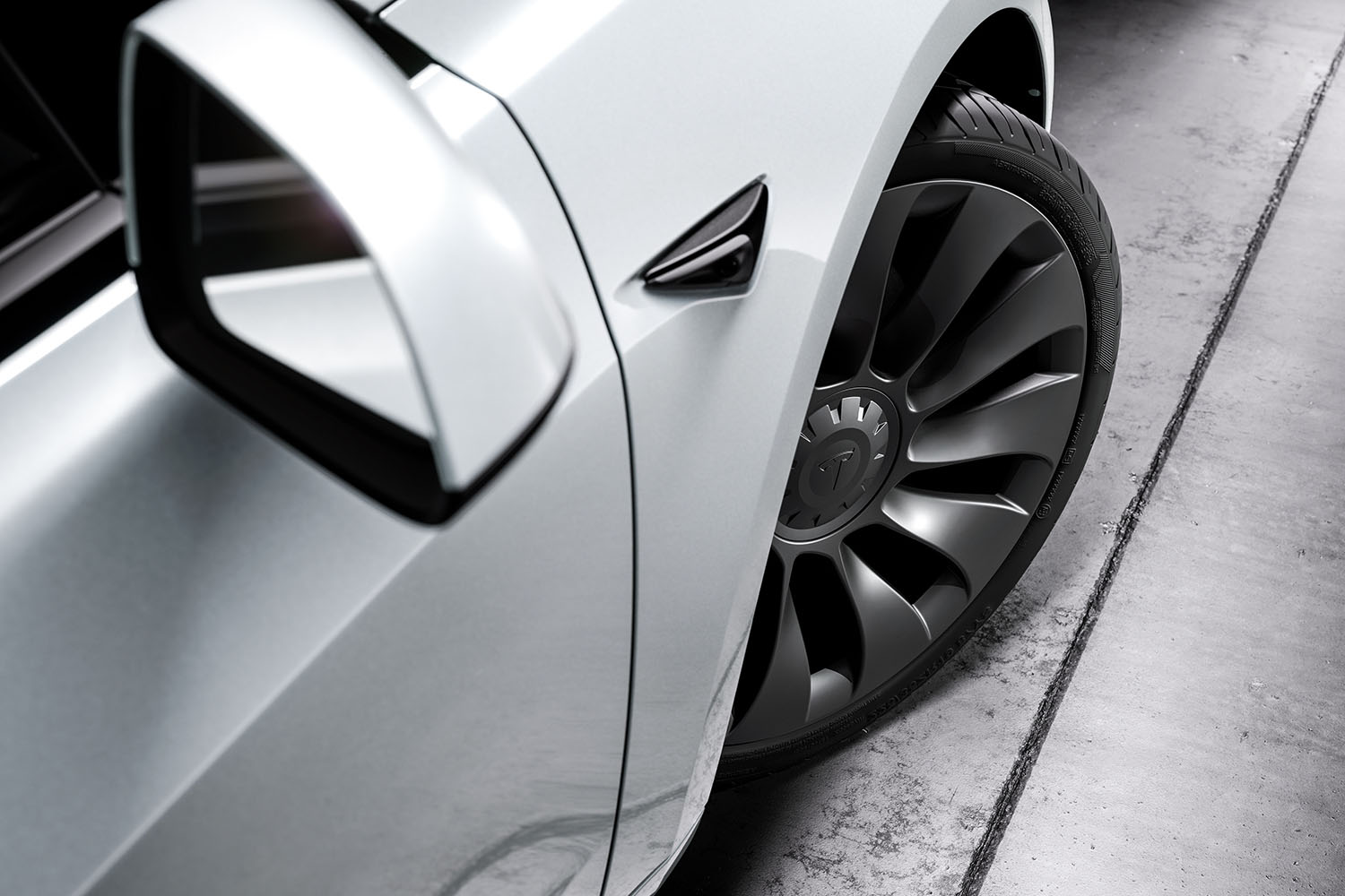 Close-up view of passenger-side white Tesla Model 3 tire and side-view mirror.
