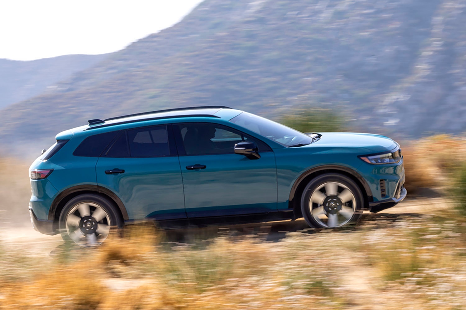  Blue 2024 Honda Prologue driving on a dirt road in the mountains.