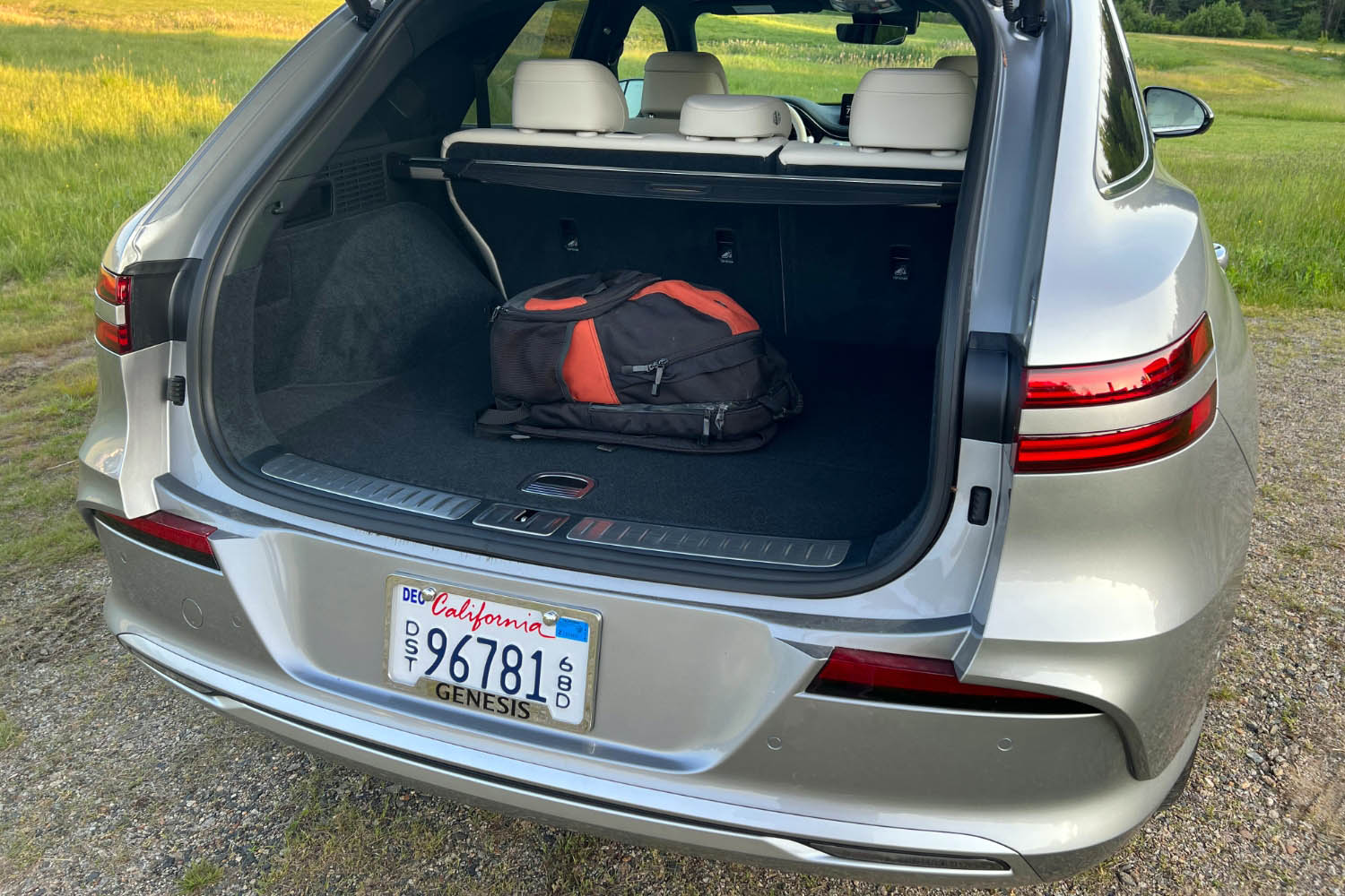 2023 Genesis Electrified GV70 in Savile Silver with the rear hatch open displaying the cargo space with a backpack stowed for perspective.