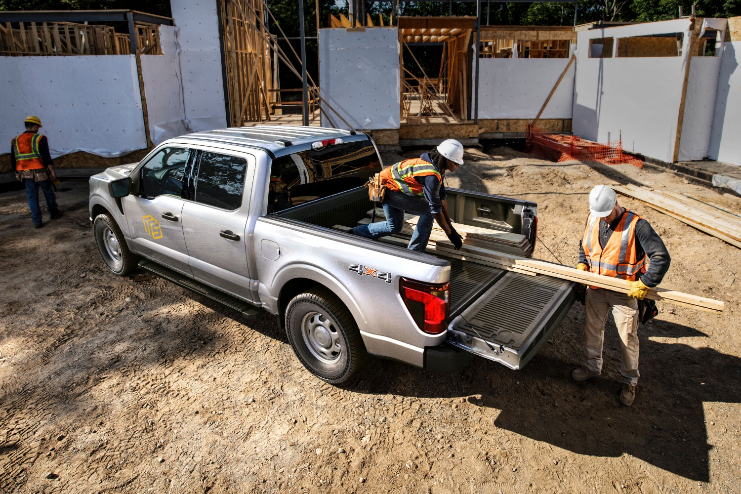 2024 Ford F-150 XL with several construction workers unloading lumber at a worksite.