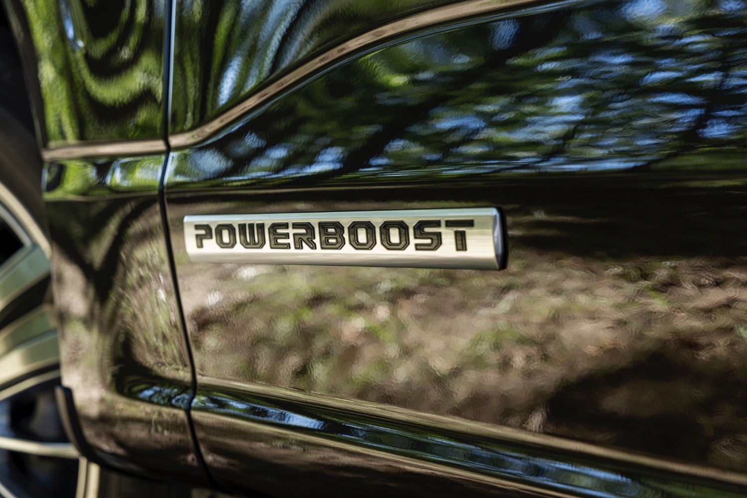 Close-up of 2024 Ford F-150 PowerBoost badge on side of black truck.