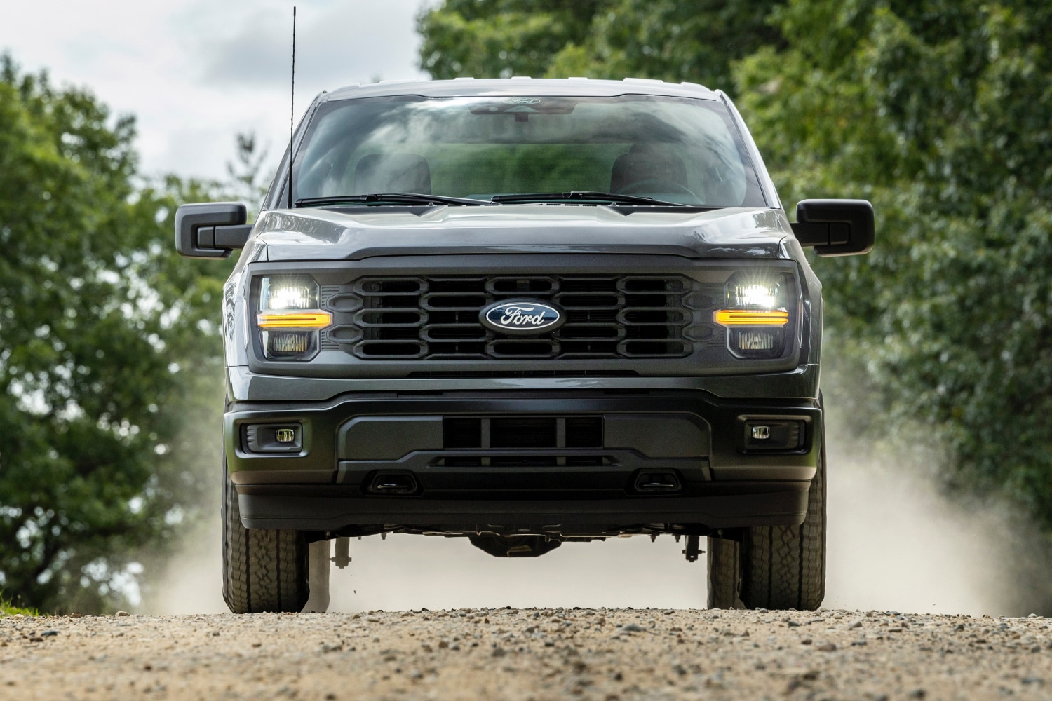 2024 Ford F-150 STX in Gray driving on dirt path.