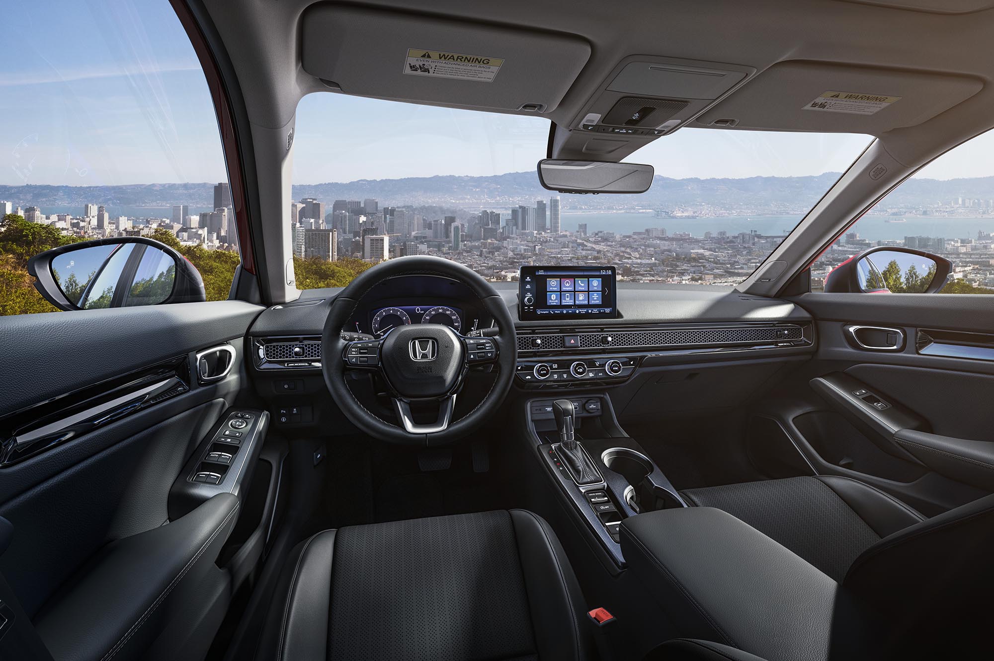 Front seats of current-generation Honda Civic with view out windshield of cityscape