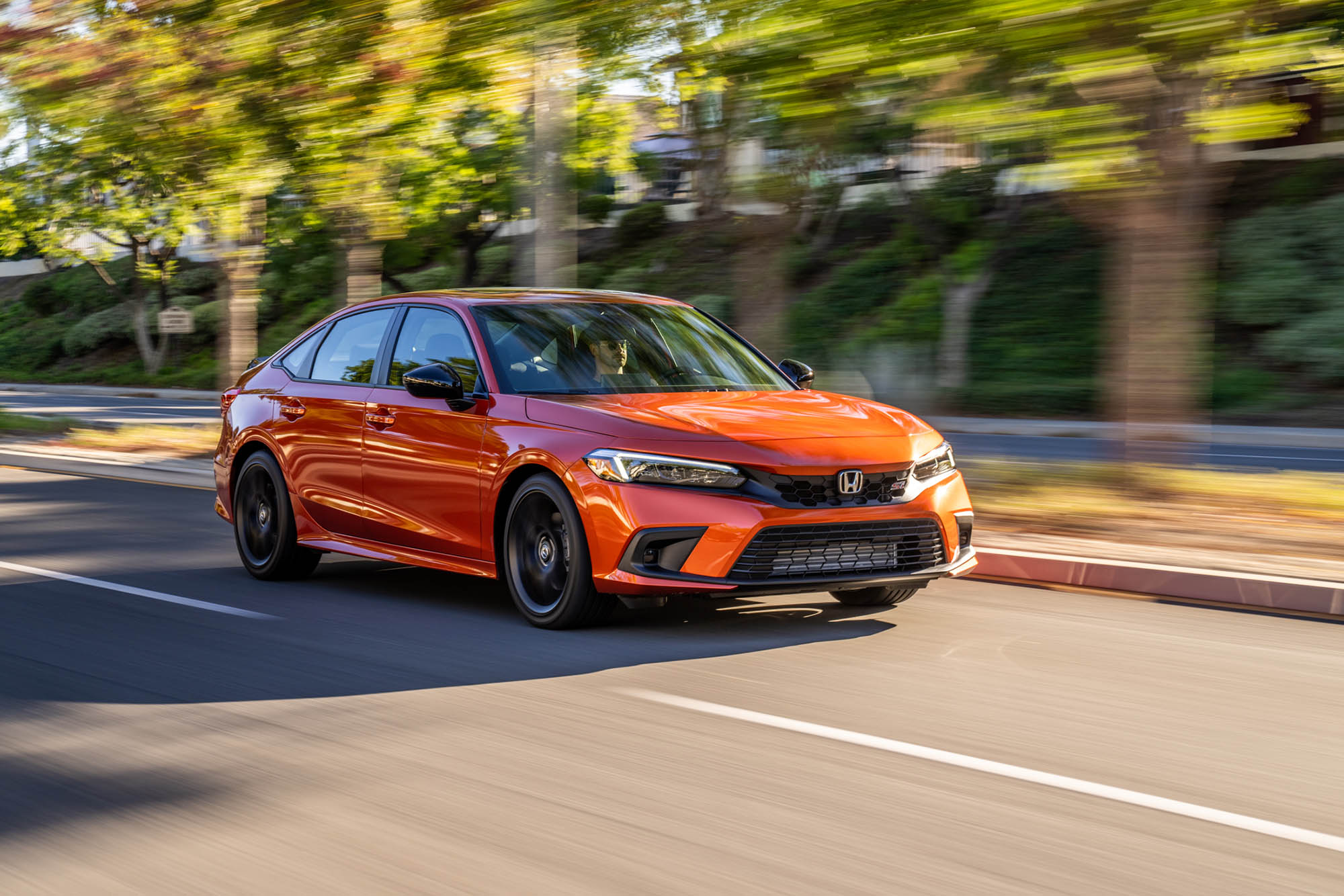  Red-orange current-generation Honda Civic driving on paved road