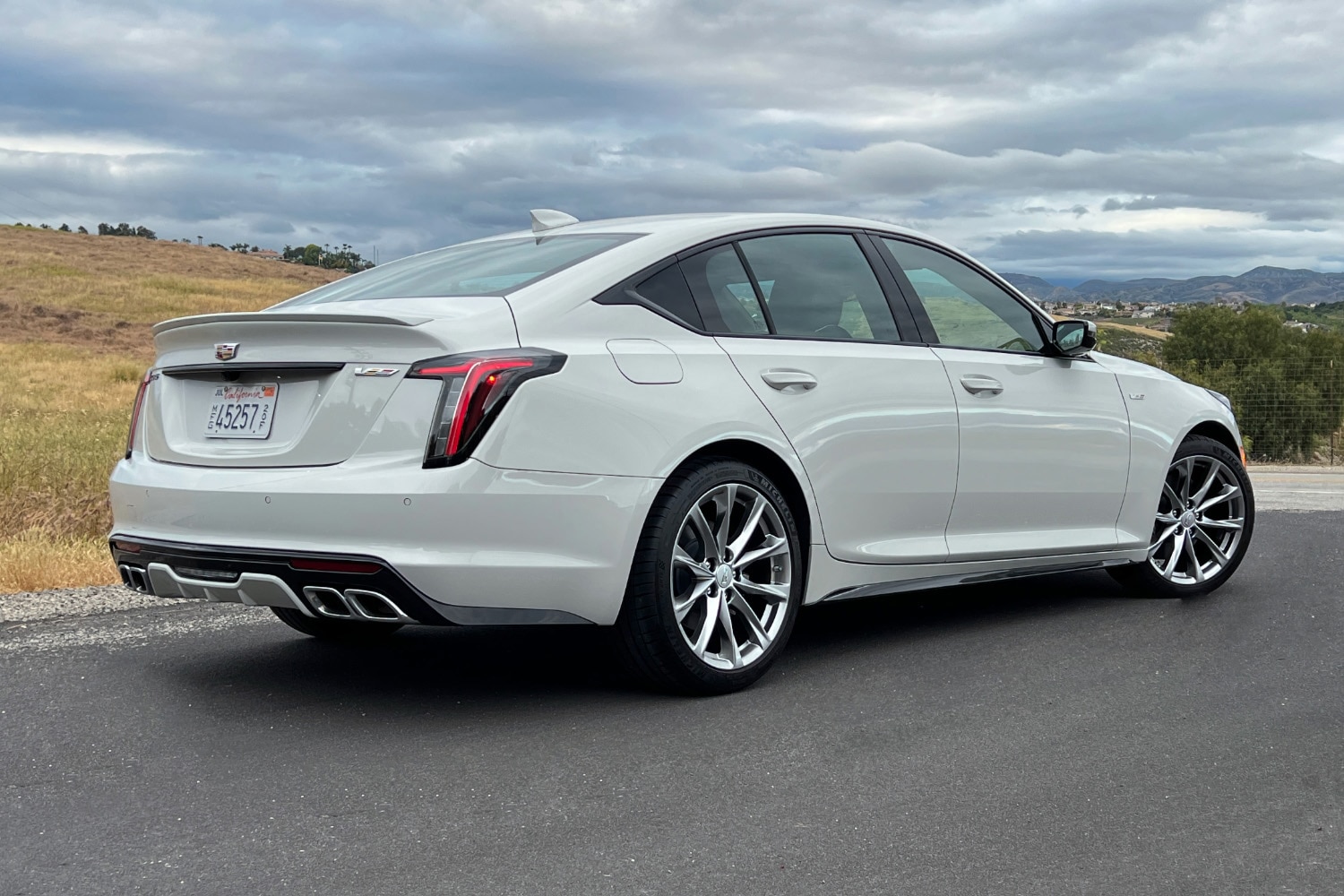 Rear right quarter view of a white 2023 Cadillac CT5-V under a cloudy sky
