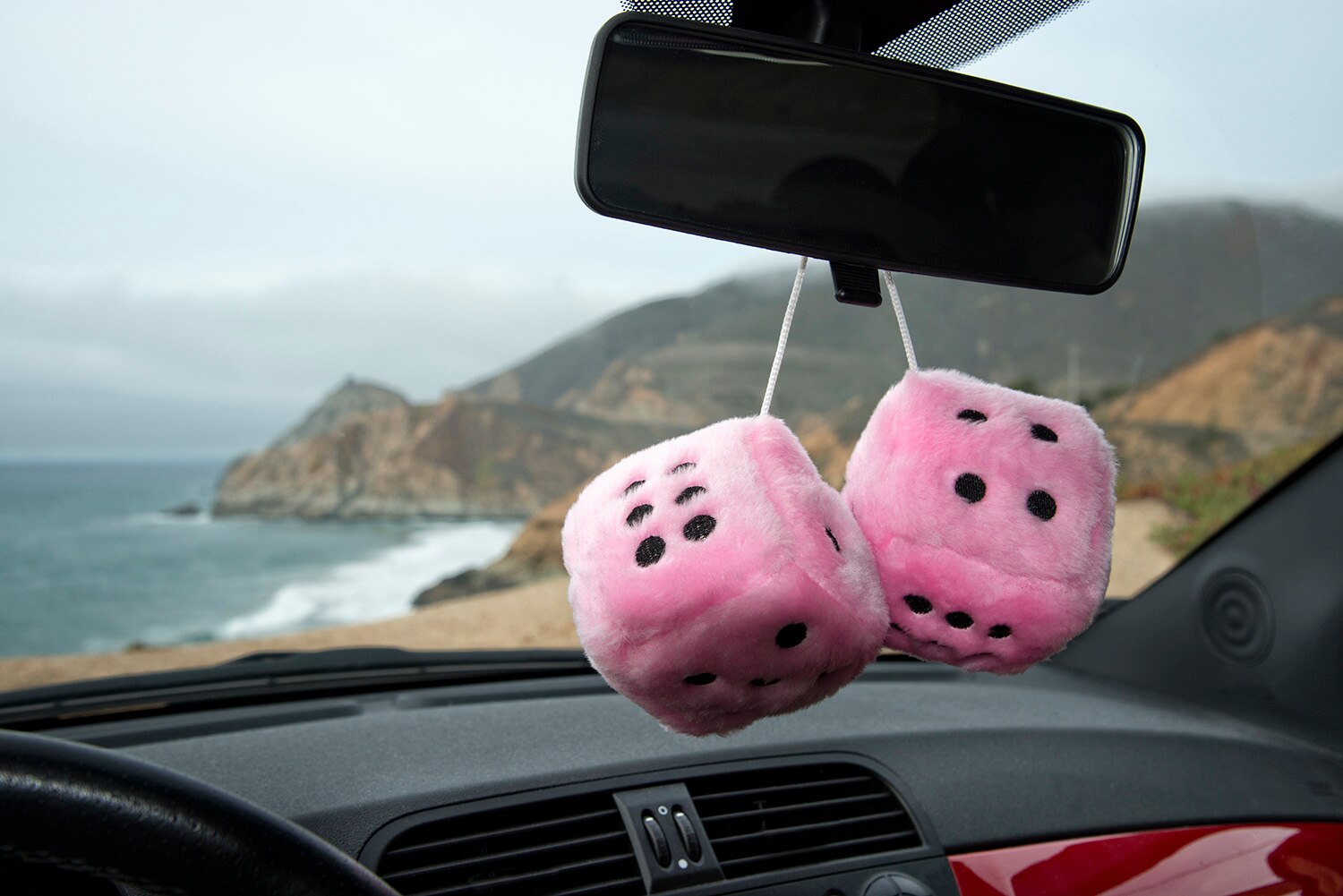 Pink fuzzy stuffed dice hang from rearview mirror