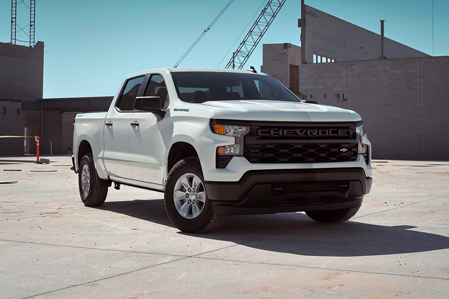 White 2023 Chevrolet Silverado 1500 WT is parked at a construction site.