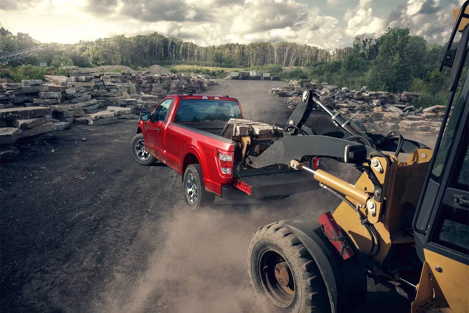 2023 Ford F-150 XL is parked in a quarry getting rocks loaded in the bed by heavy equipment.