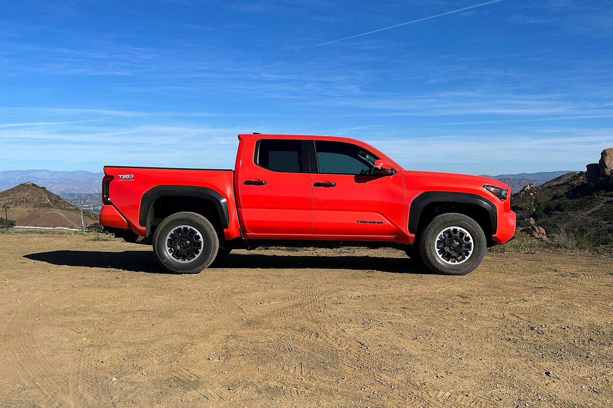 Orange 2024 Toyota Tacoma Off-Road side view parked in the mountains