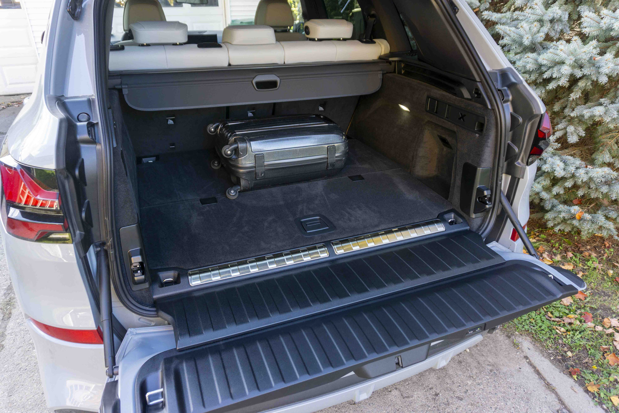 2024 BMW X5 xDrive50e cargo area with small suitcase and open tailgate and liftgate