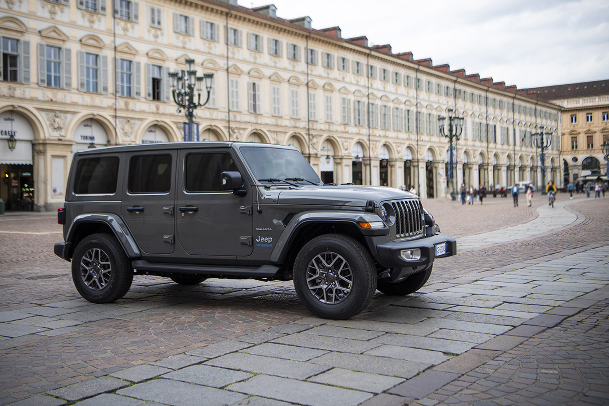 Gray Jeep Wrangler 4Xe Sahara parked on cobblestone next to building