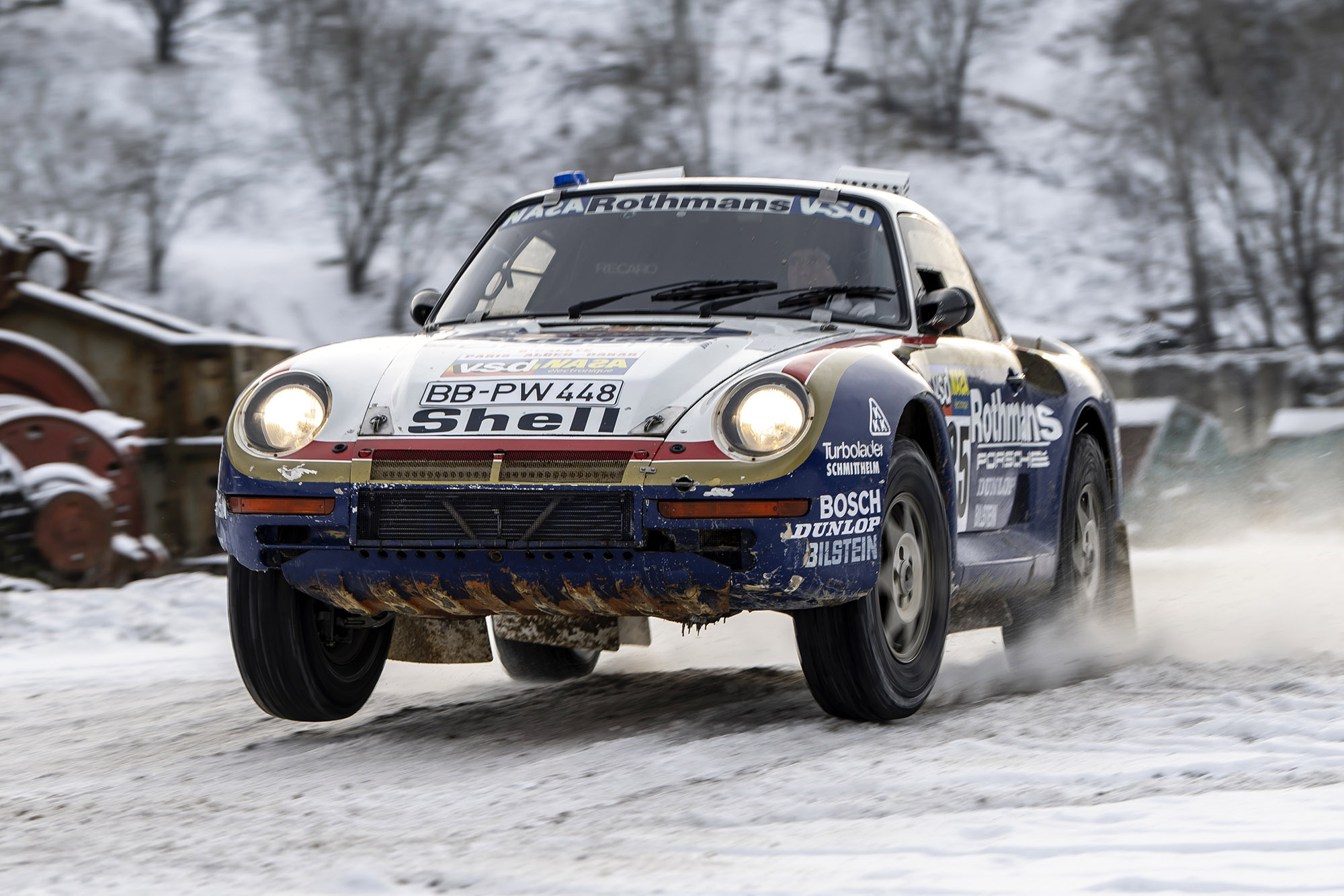 Porsche 959 rally car wearing a race livery driving in the snow