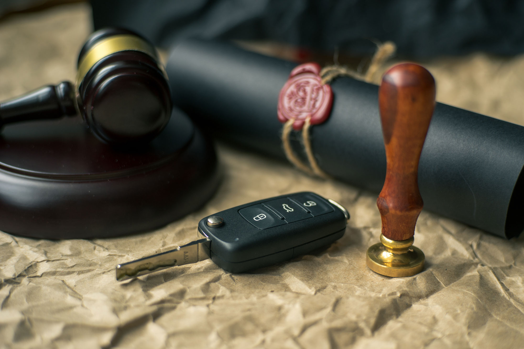 Gavel, car key, and scroll of will on table