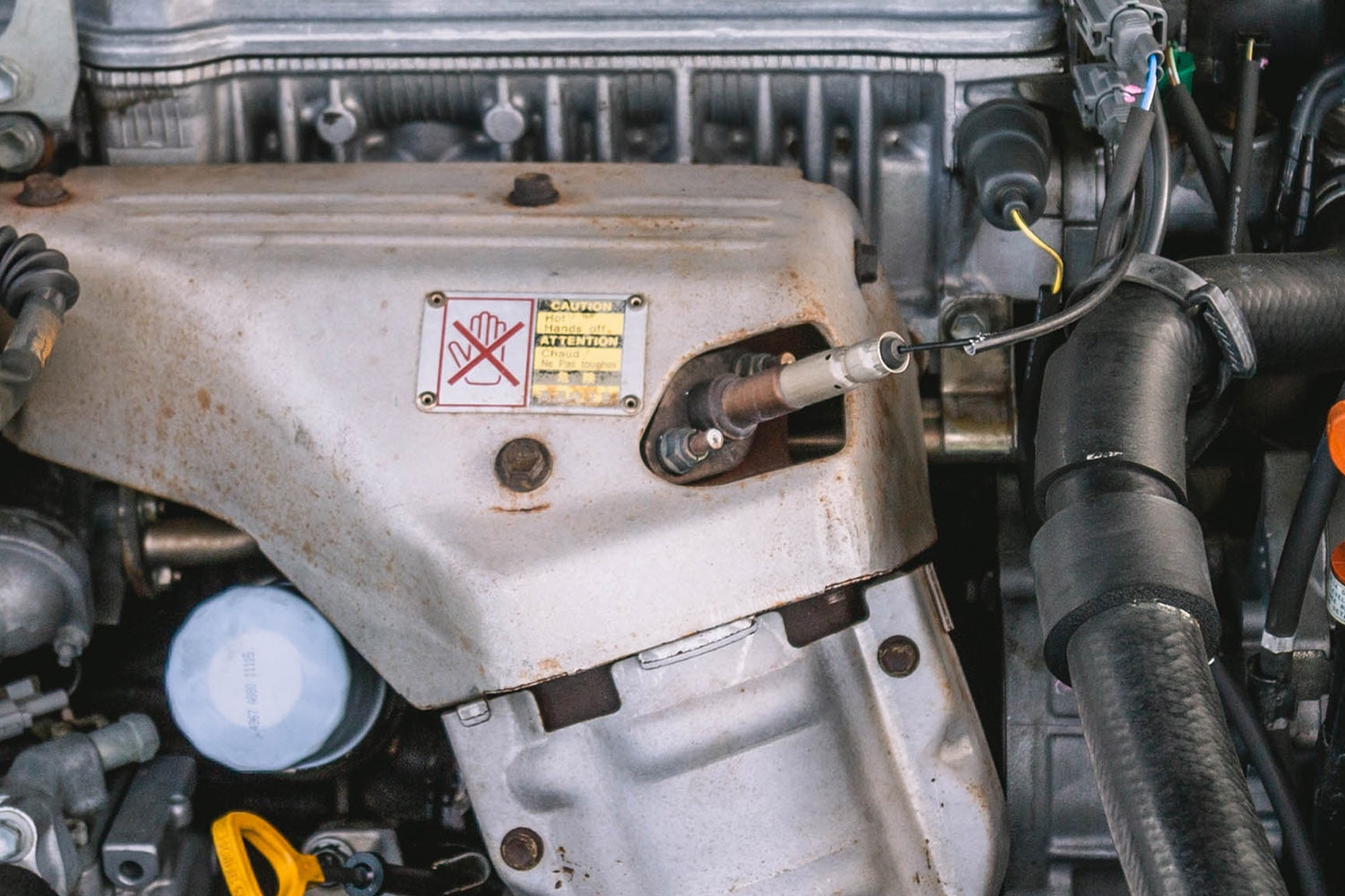 Oxygen sensor beneath the hood of a car