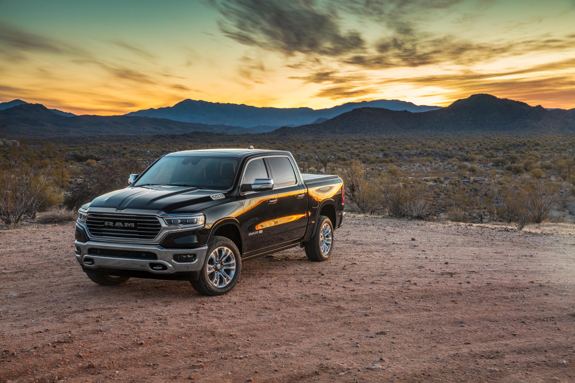 2023 Ram 1500 is parked on a dirt road in the desert at dusk.