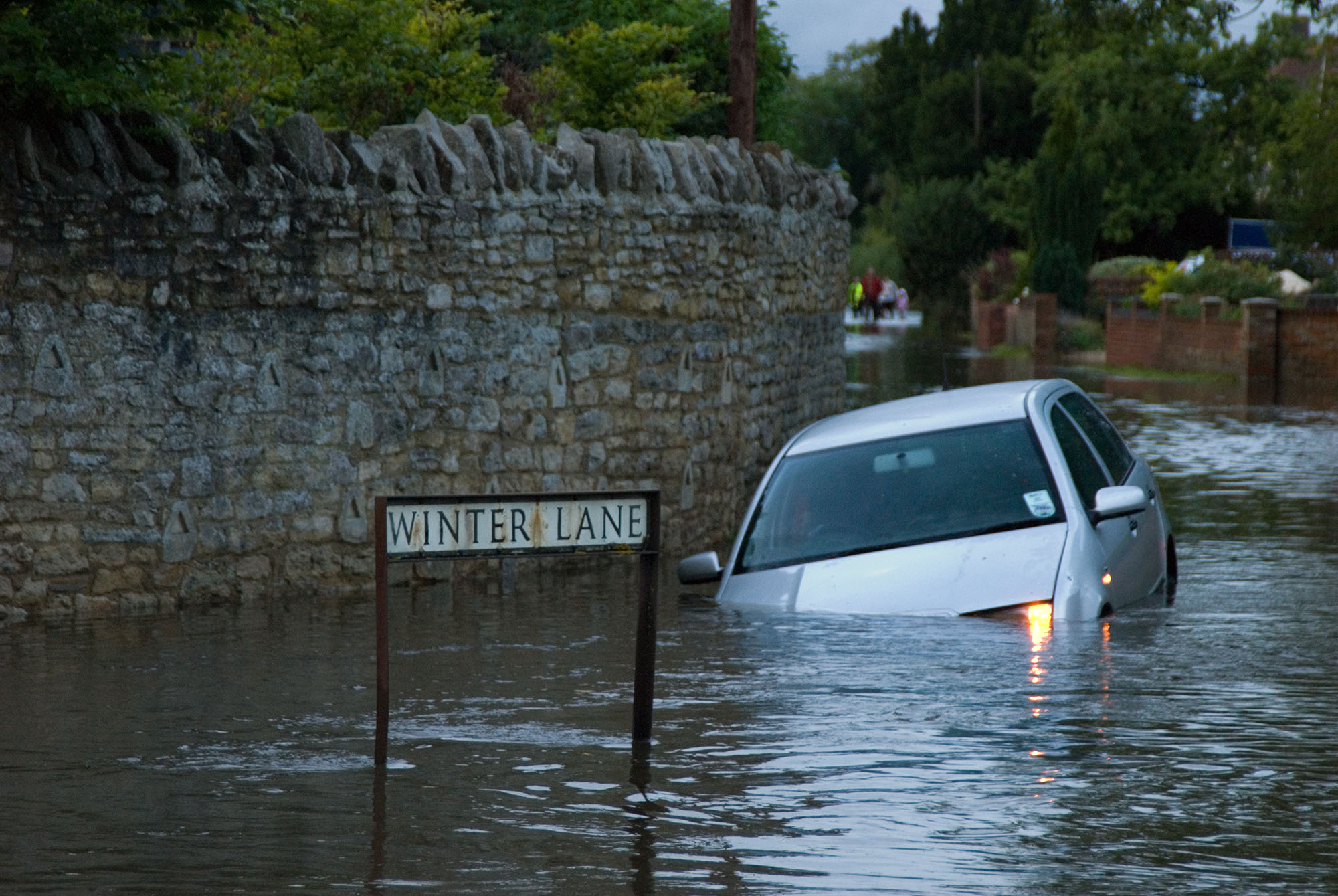 A car sinks halfway into water on a flooded street