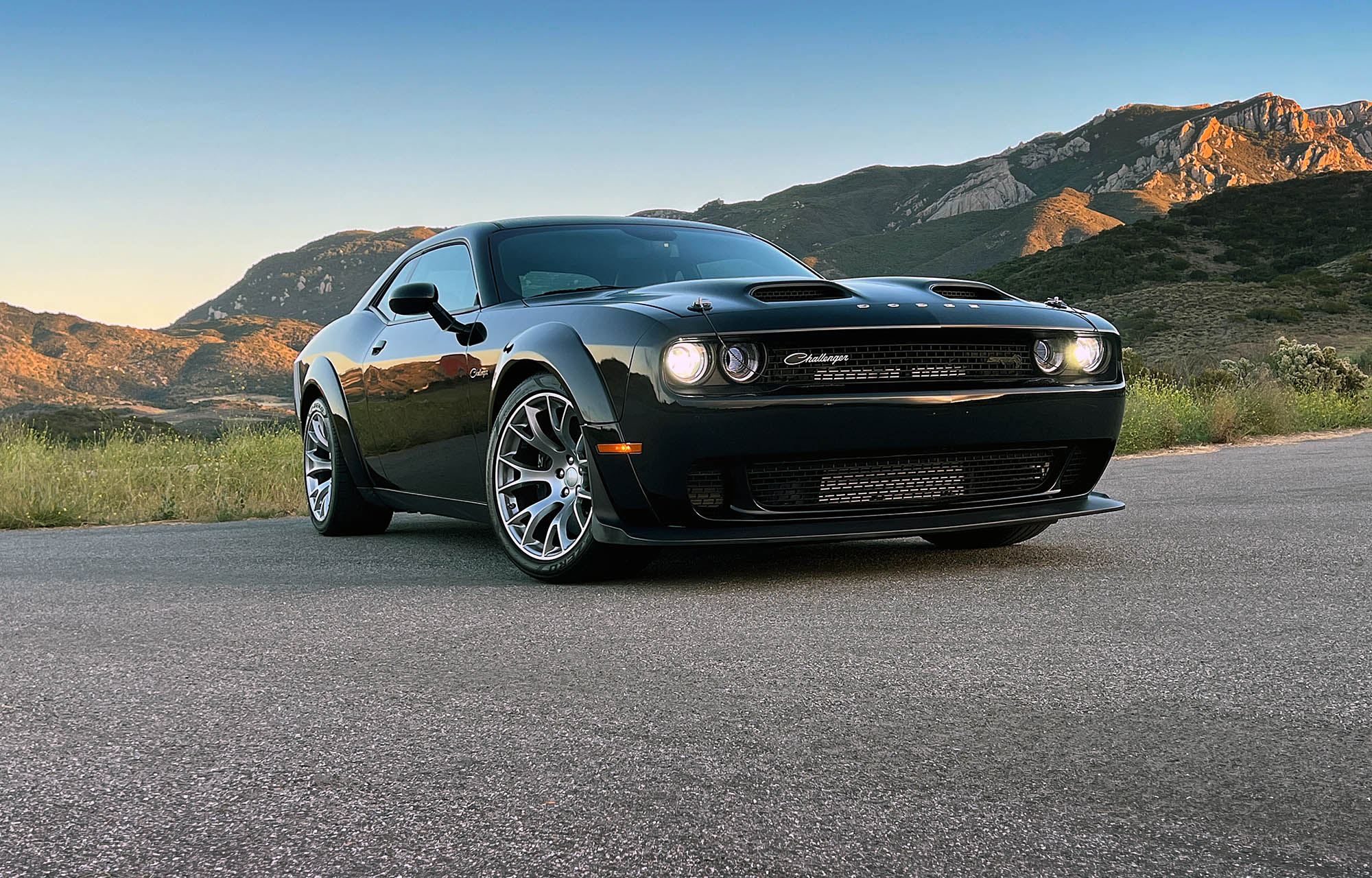 2023 Dodge Challenger Black Ghost front three-quarter view with mountains in the background.