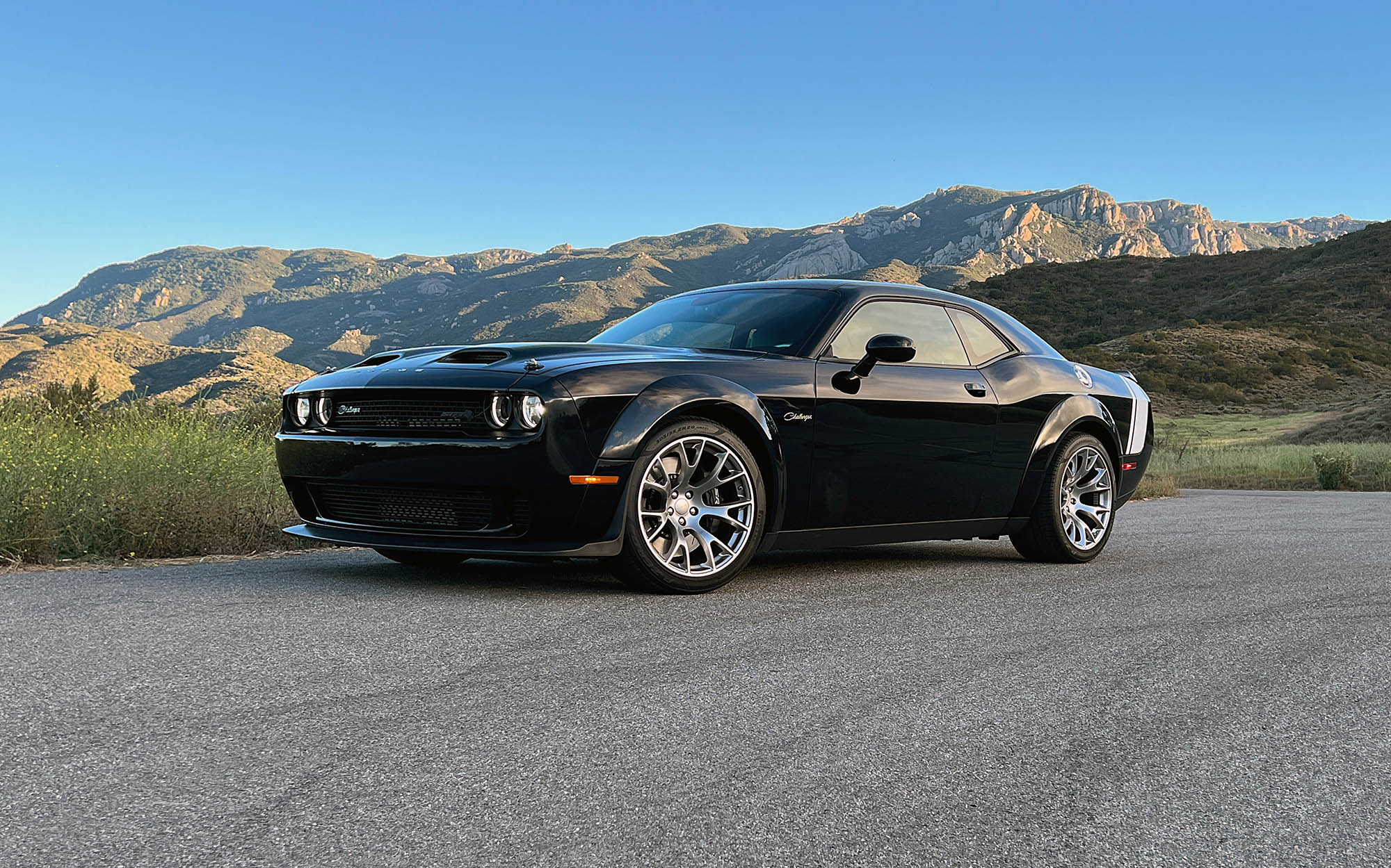 2023 Dodge Challenger Black Ghost front three-quarter view with mountains in the background.