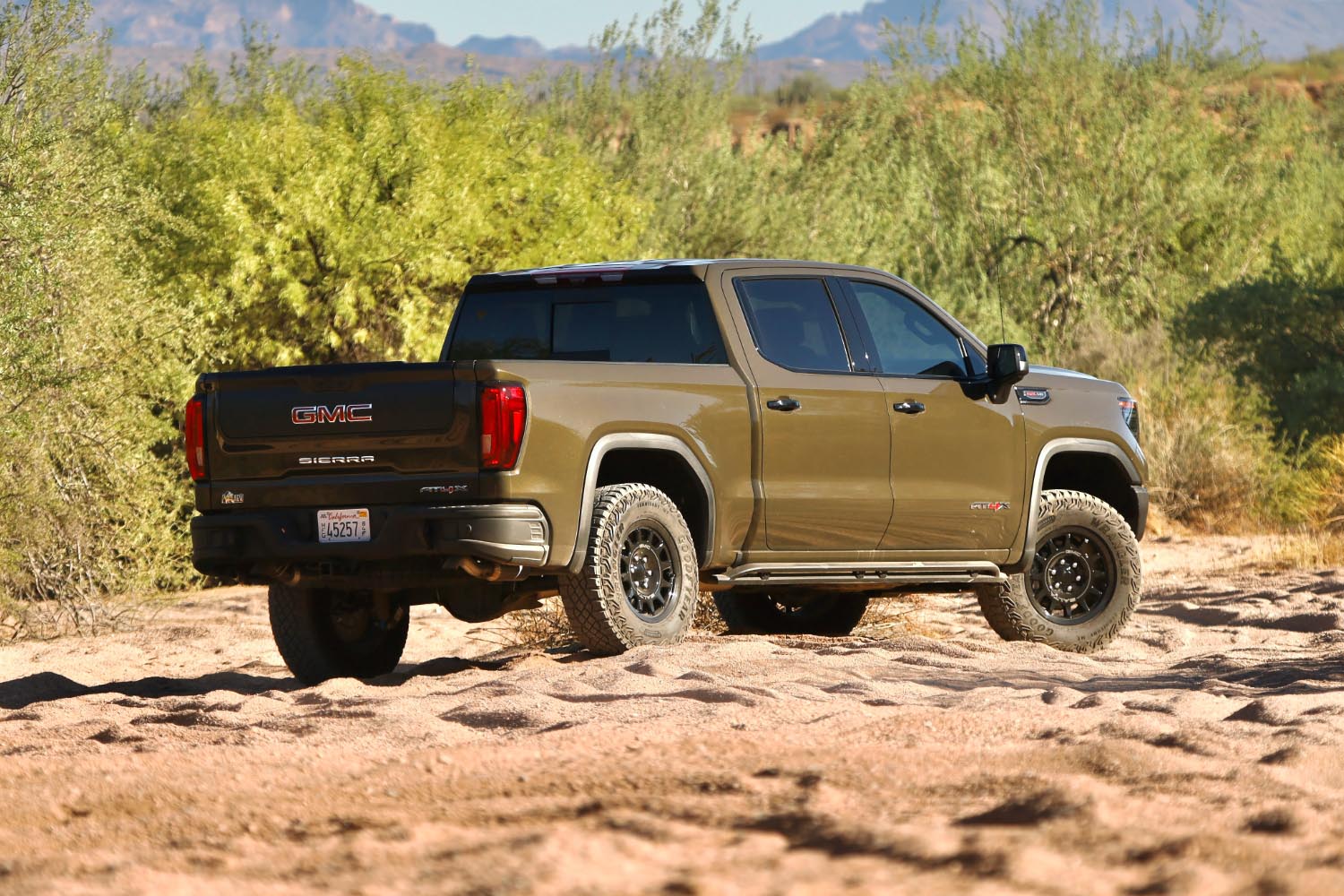 Rear right quarter view of a brown 2023 GMC Sierra 1500 AT4X in the dessert