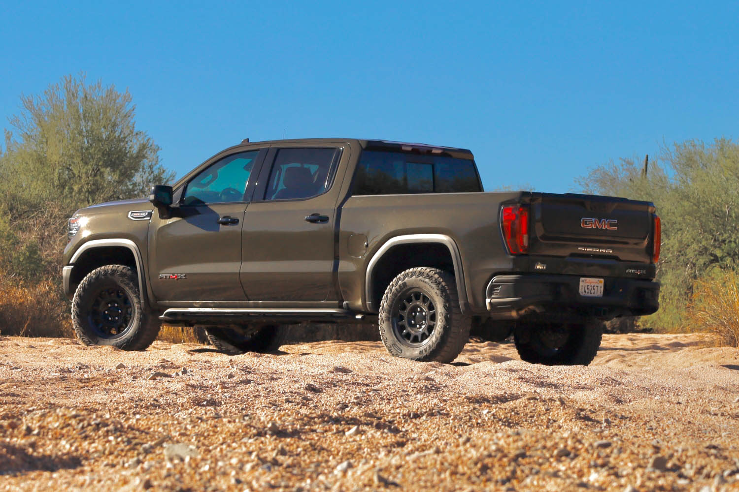 Rear left quarter view of a brown 2023 GMC Sierra 1500 AT4X in the dessert