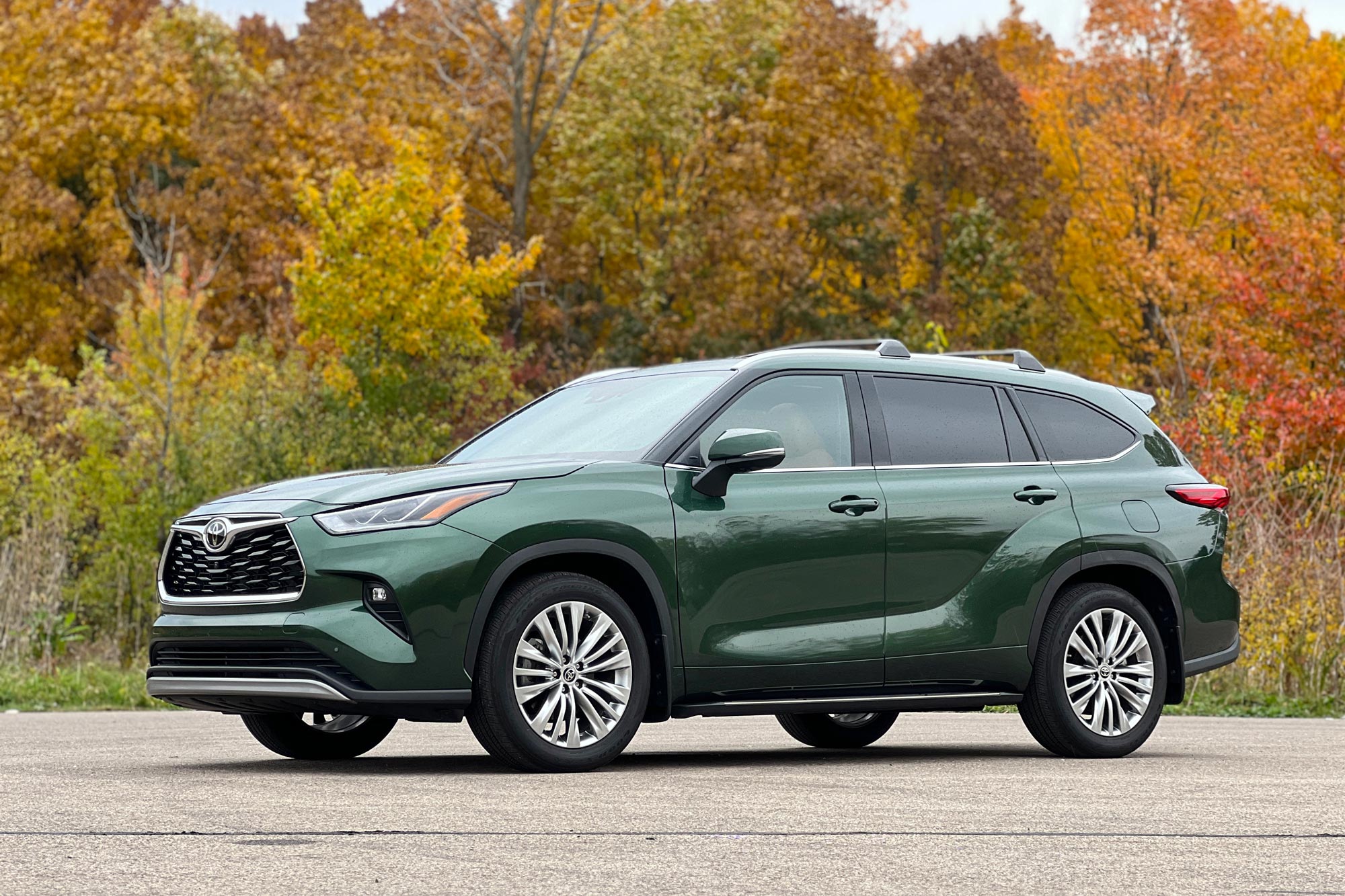 2024 Toyota Highlander in green parked on concrete by trees.