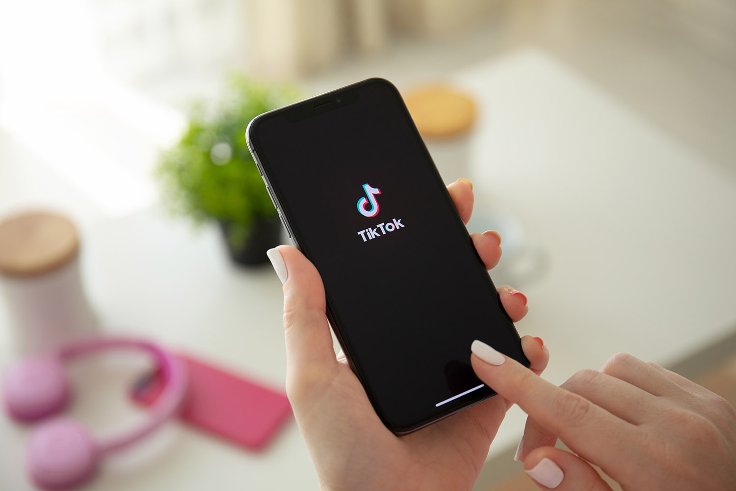 A person's hand holds a smartphone with the TikTok logo on the screen
