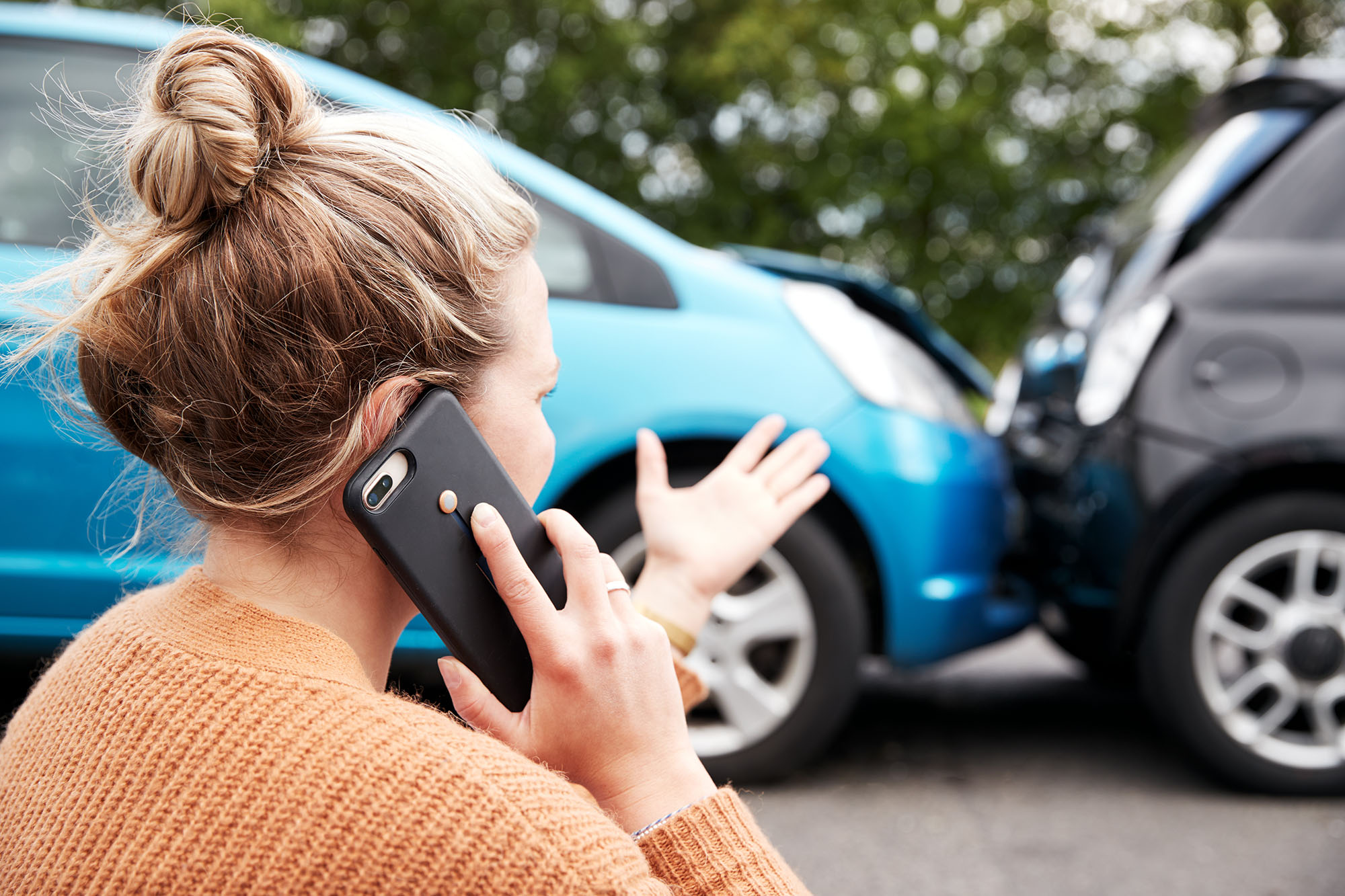 Person speaks on a mobile phone in front of a fender bender