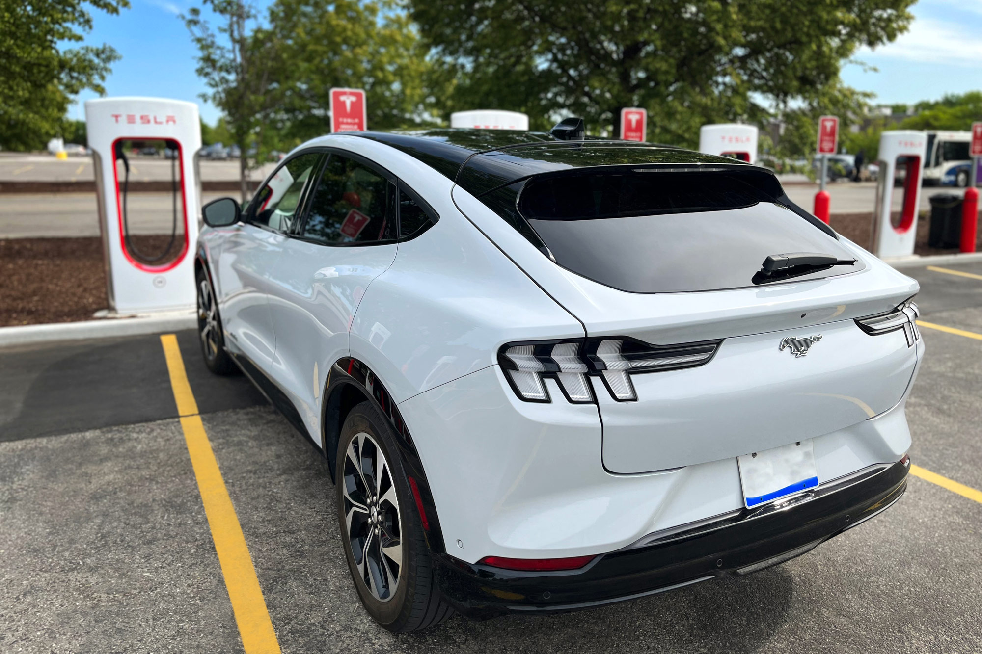A Ford Mustang Mach E parked at a Tesla charging station