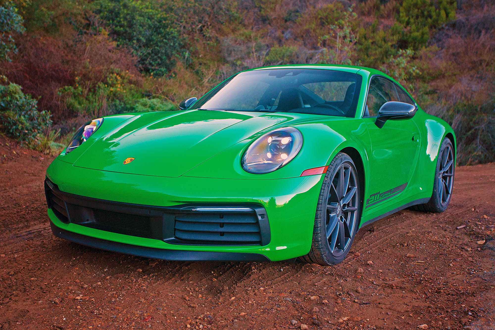 2023 Porsche 911 Carrera T in Python Green parked on dirt.