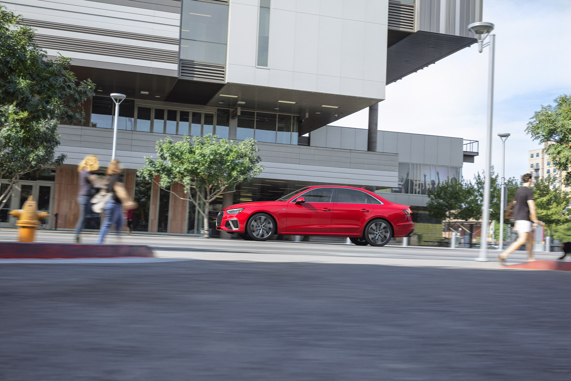 A red Audi A4 driving through a city.
