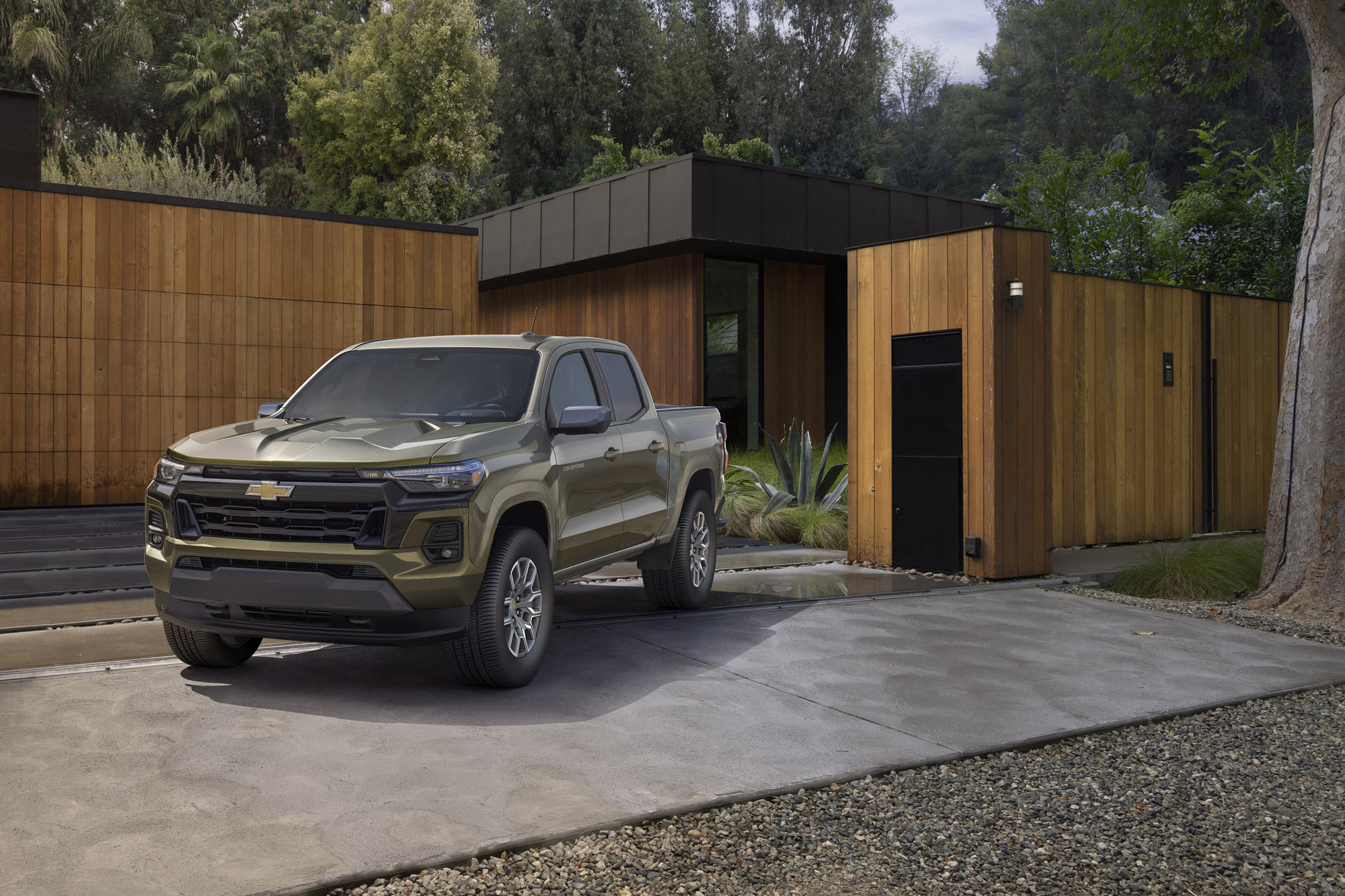 Green 2023 Chevrolet Colorado LT parked outside wooden house