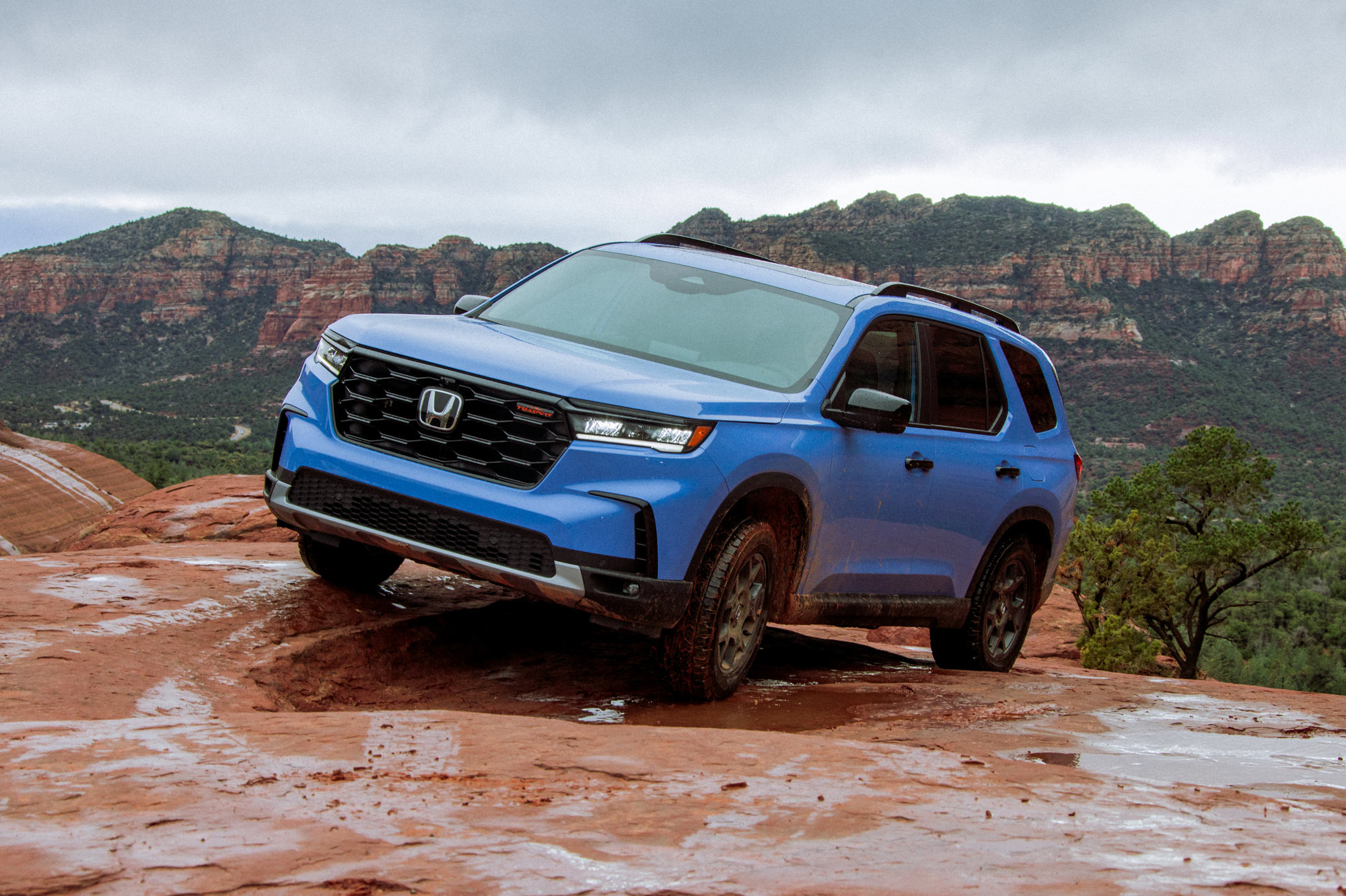 2024 Honda Pilot in blue parked on a rock in the wilderness.
