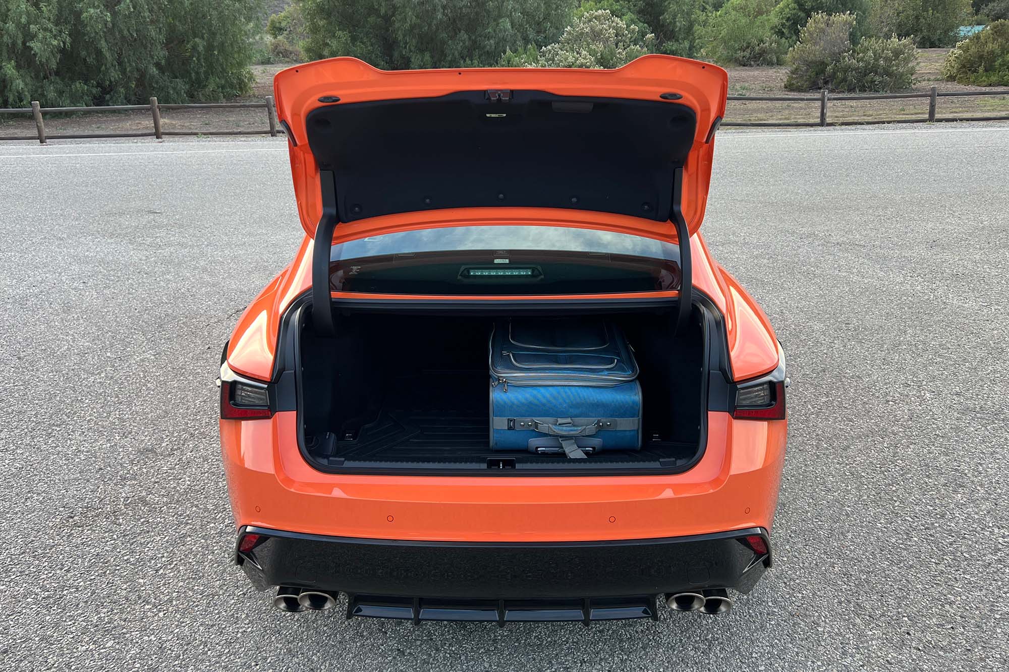 Rear view of an orange 2023 Lexus IS 500 with the trunk open
