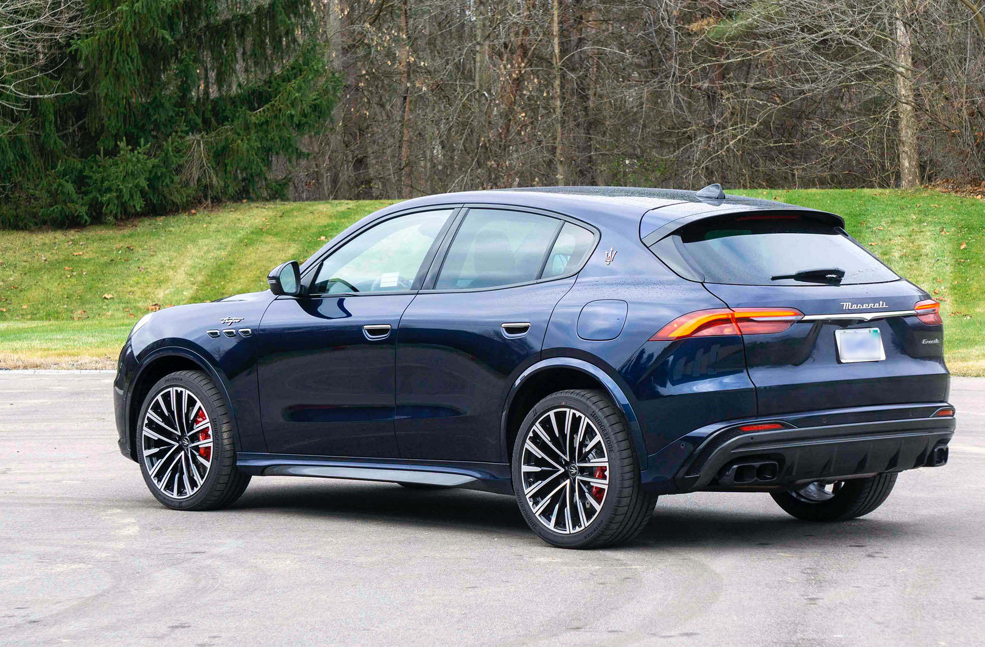 2023 Maserati Grecale in dark blue parked in front of trees and grass