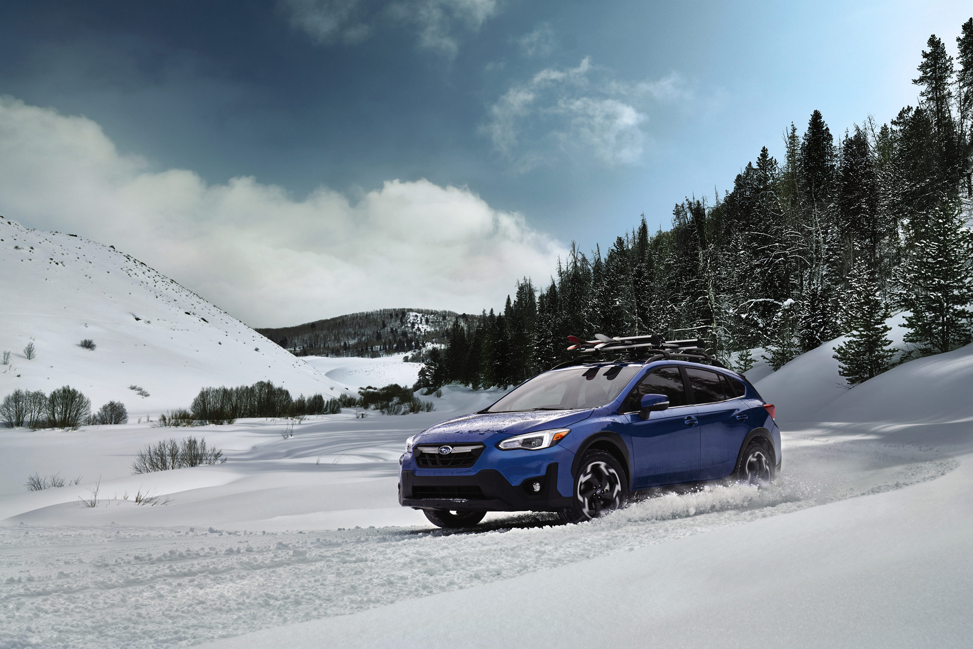 Blue 2023 Subaru Crosstrek Limited driving in snowy mountains