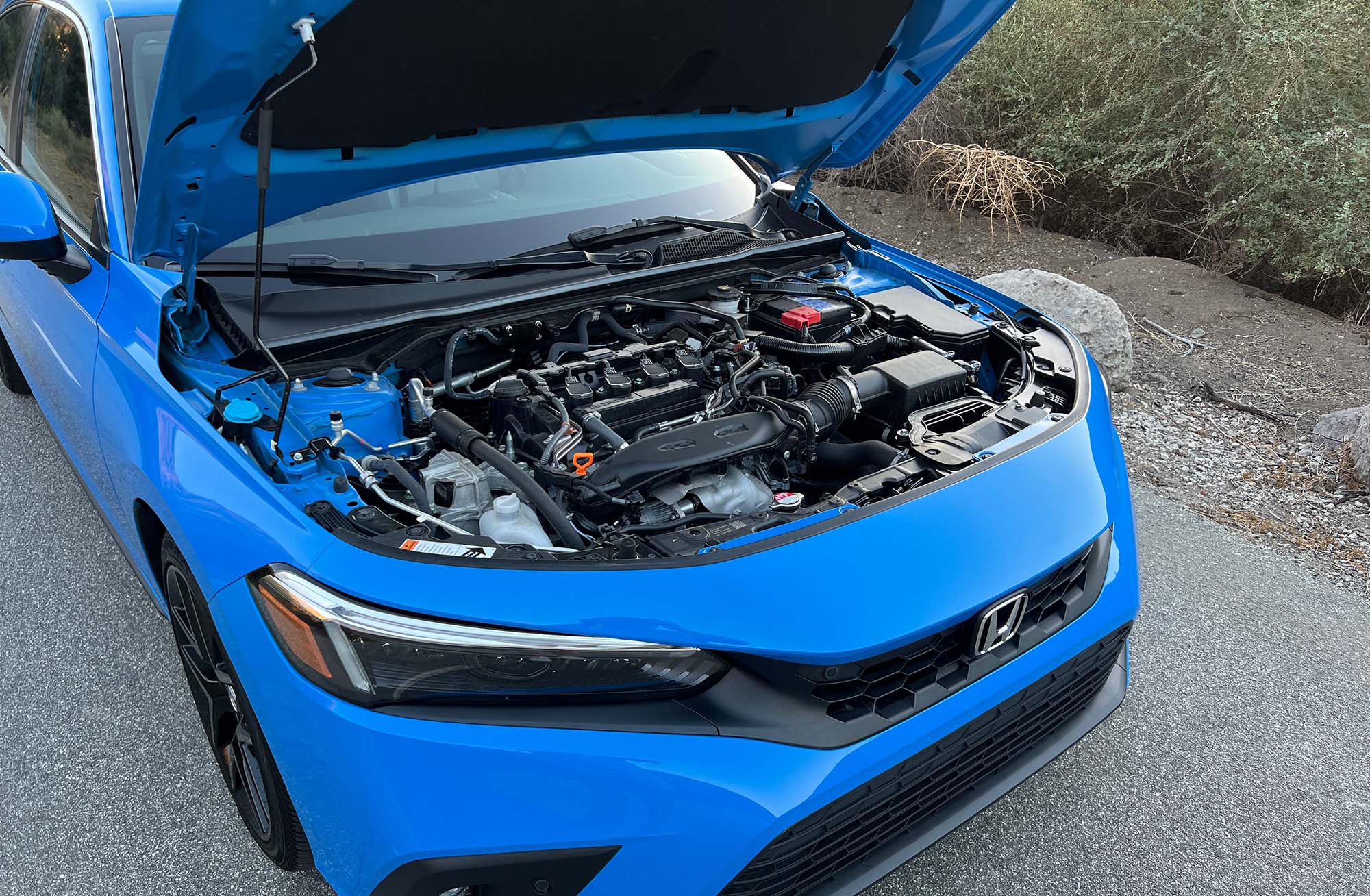 2024 Honda Civic Hatchback in bright blue with hood up and engine exposed