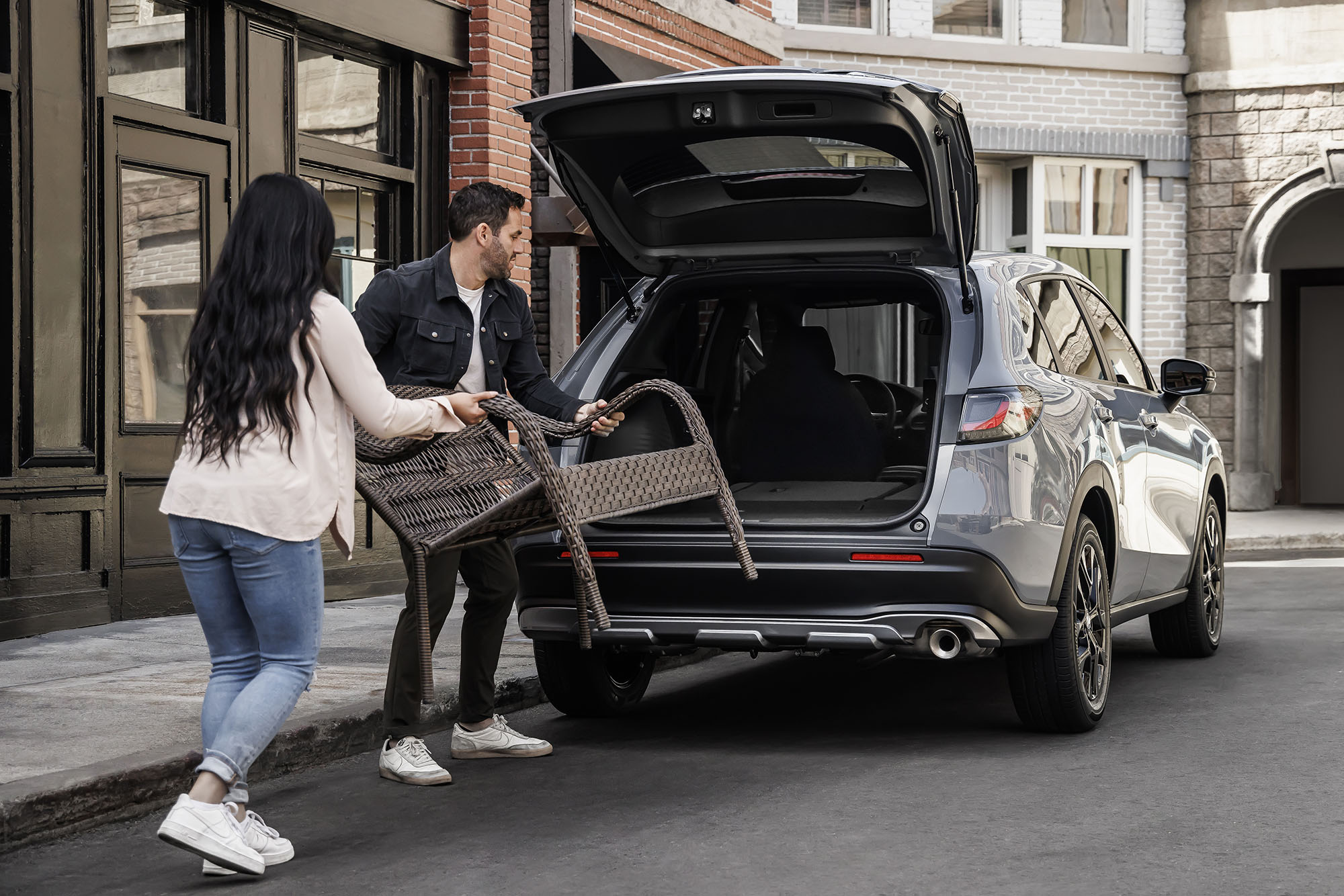 Two people load a chair into a gray Honda HR-V's rear cargo area