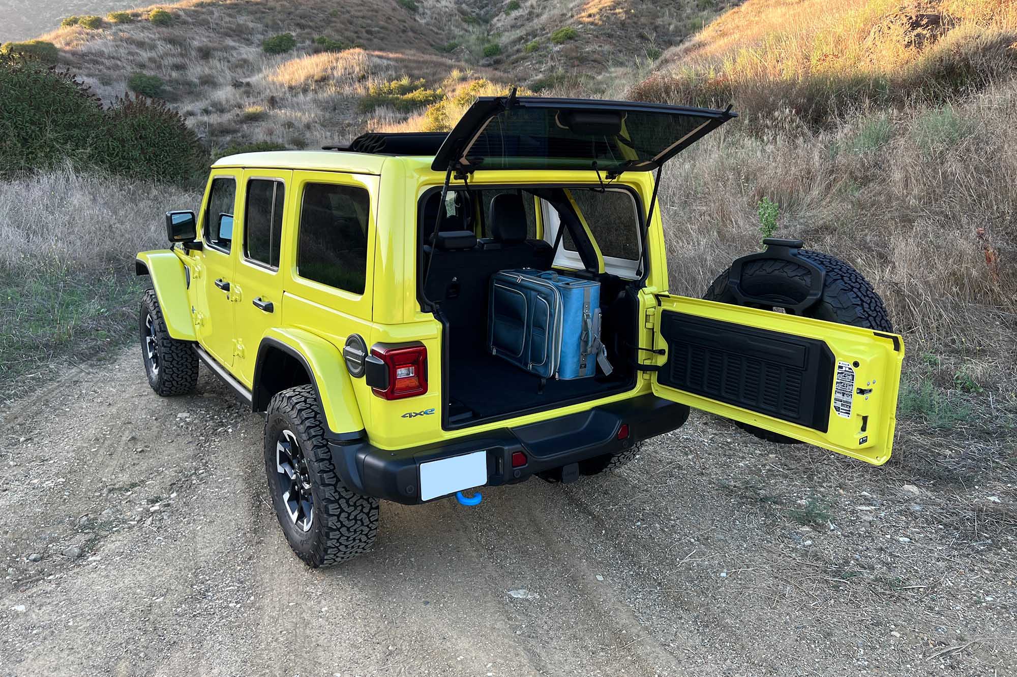 Left rear quarter view of a yellow 2024 Jeep Wrangler Rubicon 4xe with cargo area open