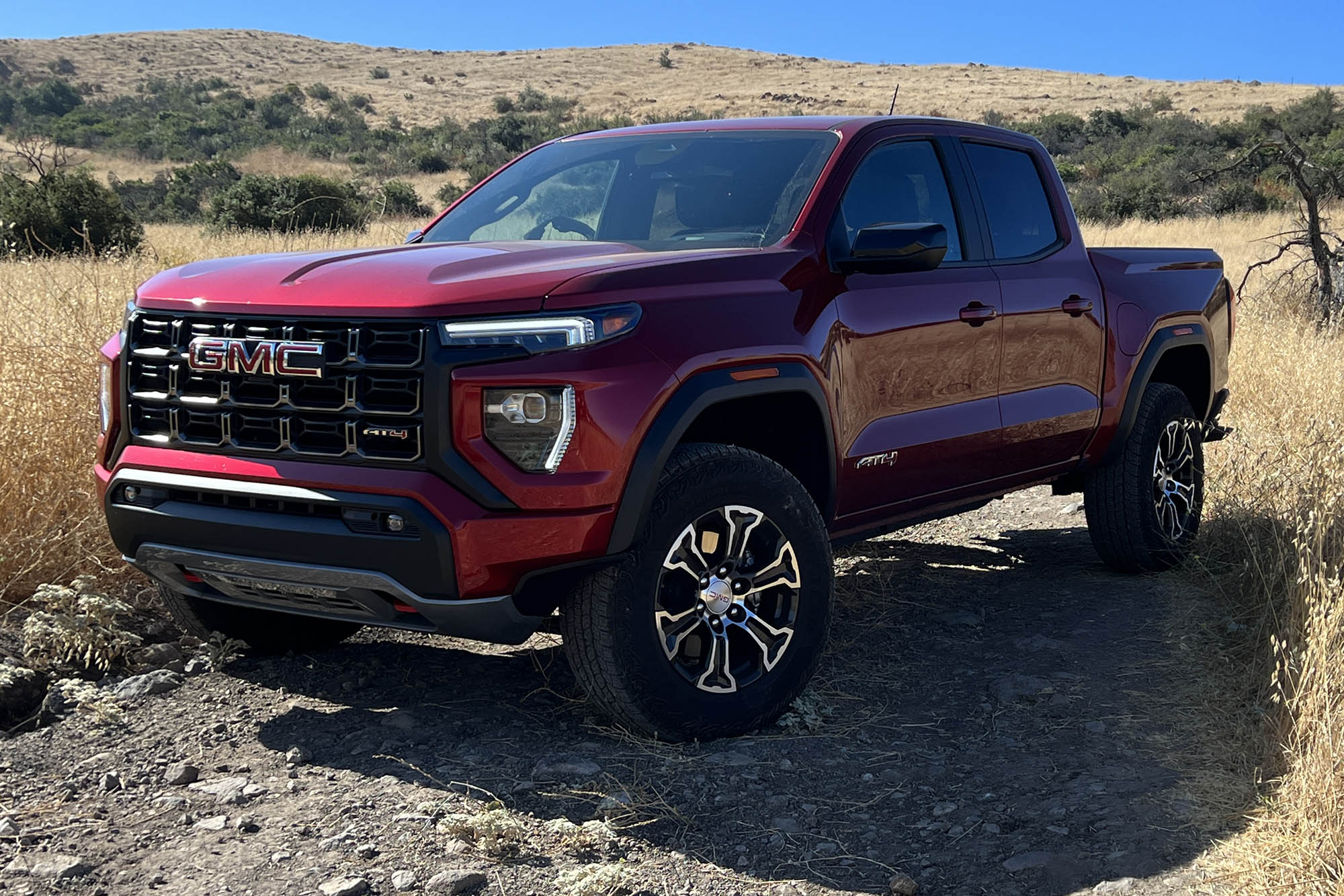 Front left quarter view of a red 2023 GMC Canyon parked on an off-road trail