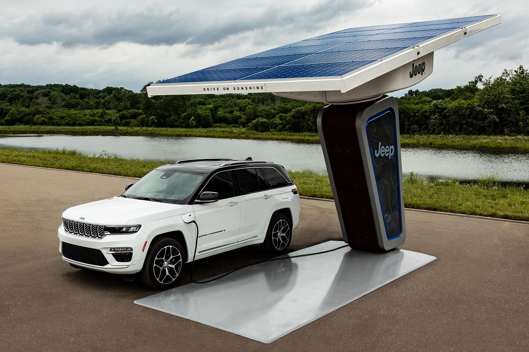 A white Jeep Grand Cherokee 4xe plugged into a solar charging station