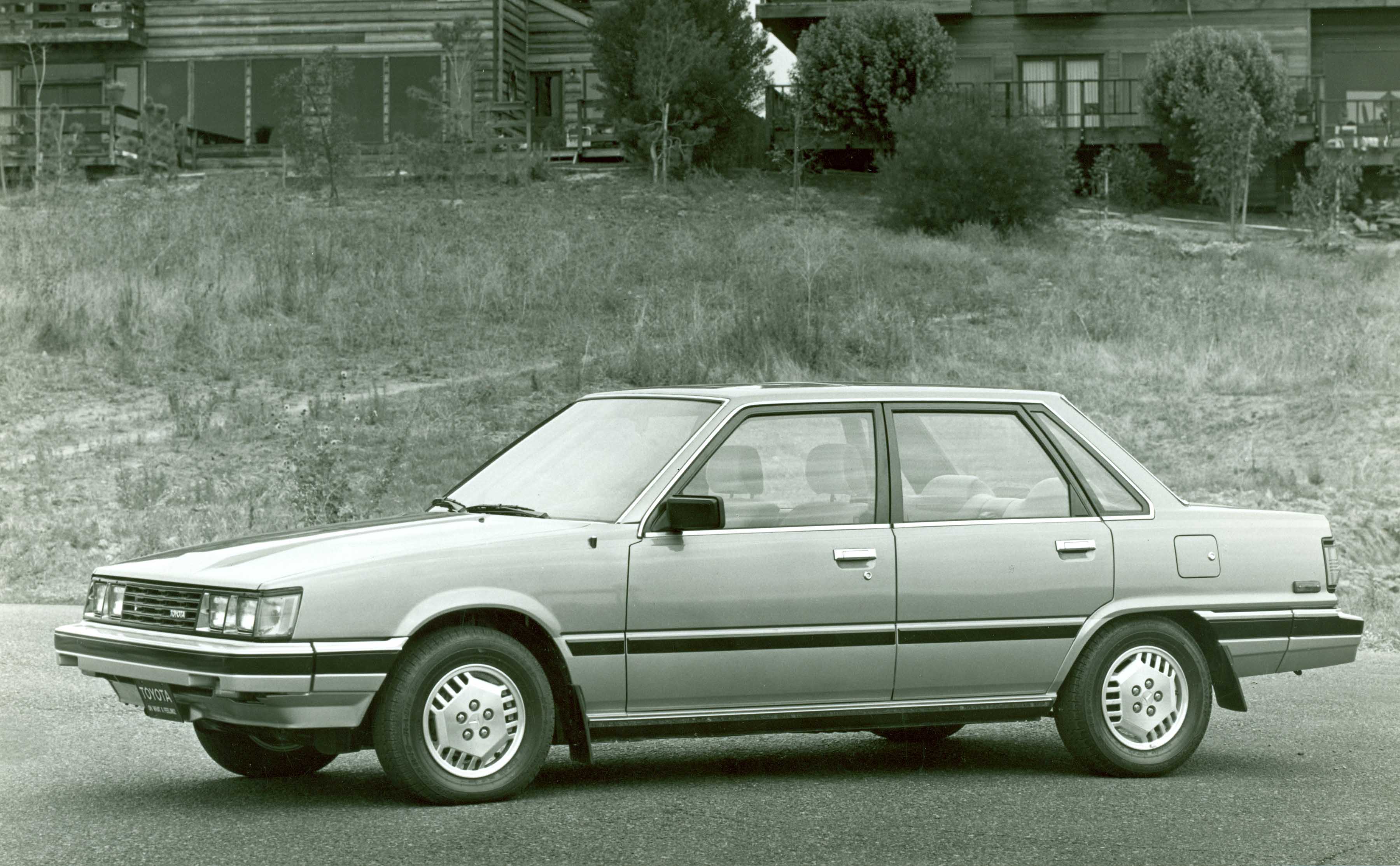 1980s Toyota Camry parked in front of houses.