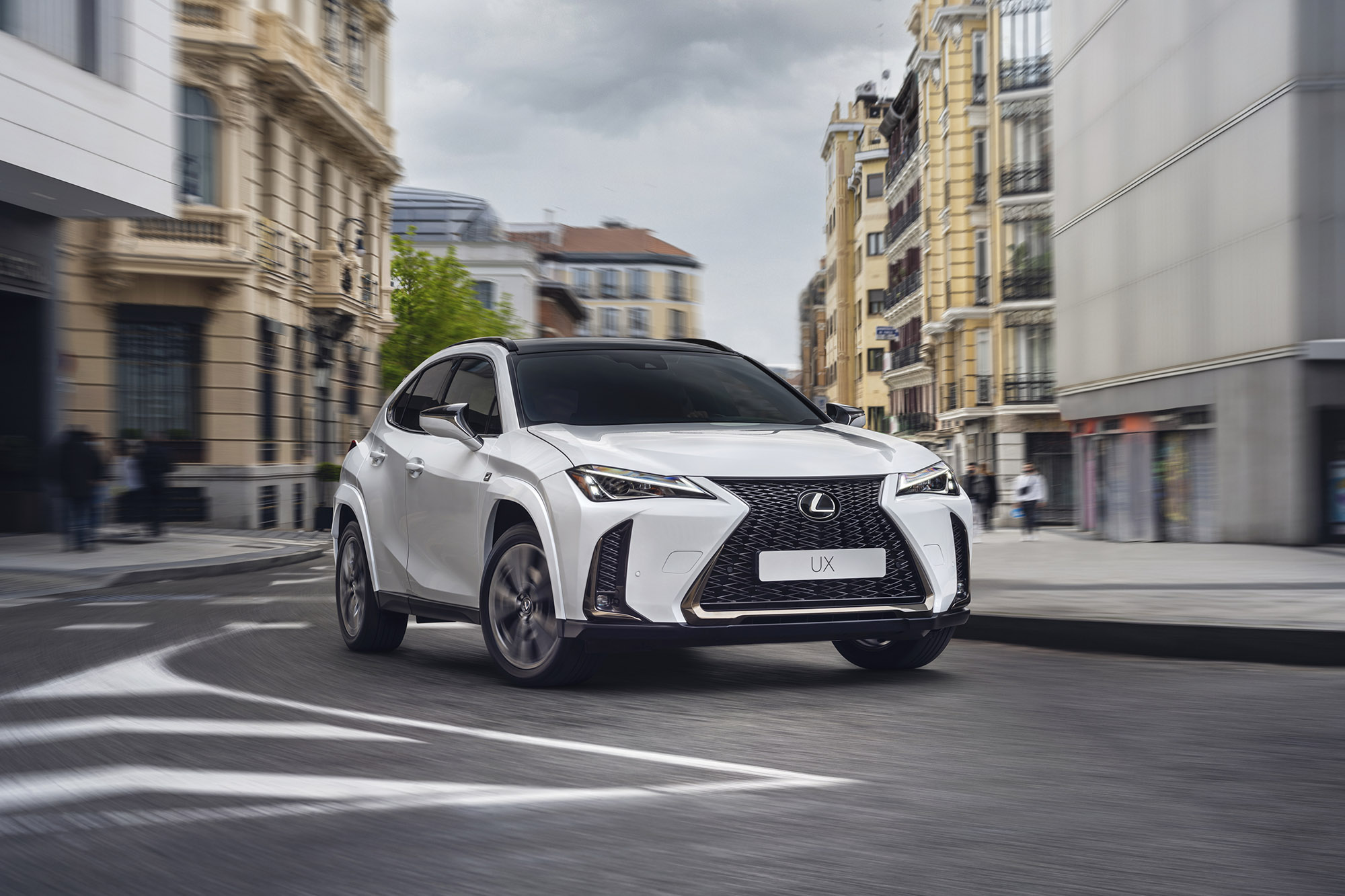 2023 Lexus UX 250h F Sport in white driving on a city street
