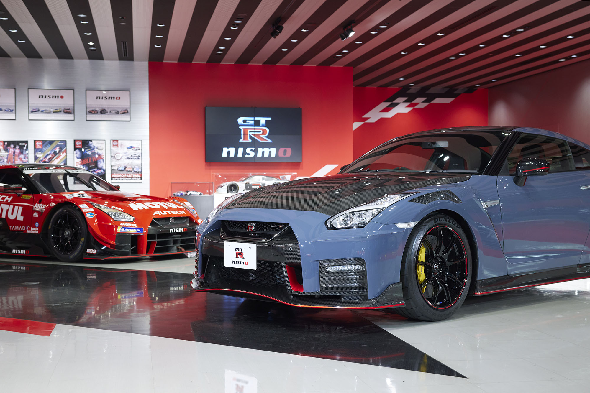 A blue 2024 Nissan GT-R Nismo in front of a red GT-R race car