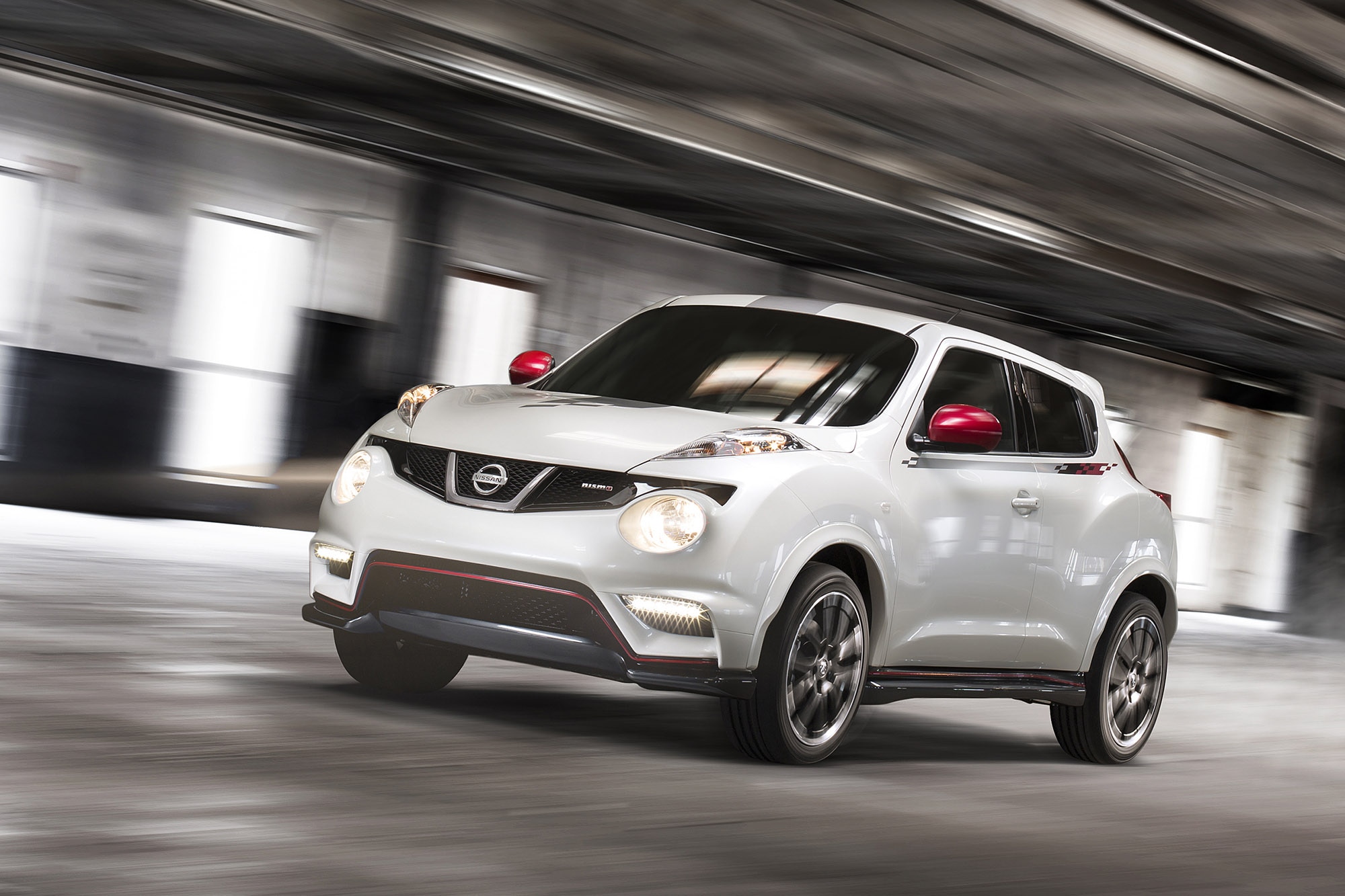 A white 2017 Nissan Juke Nismo driving in a parking garage